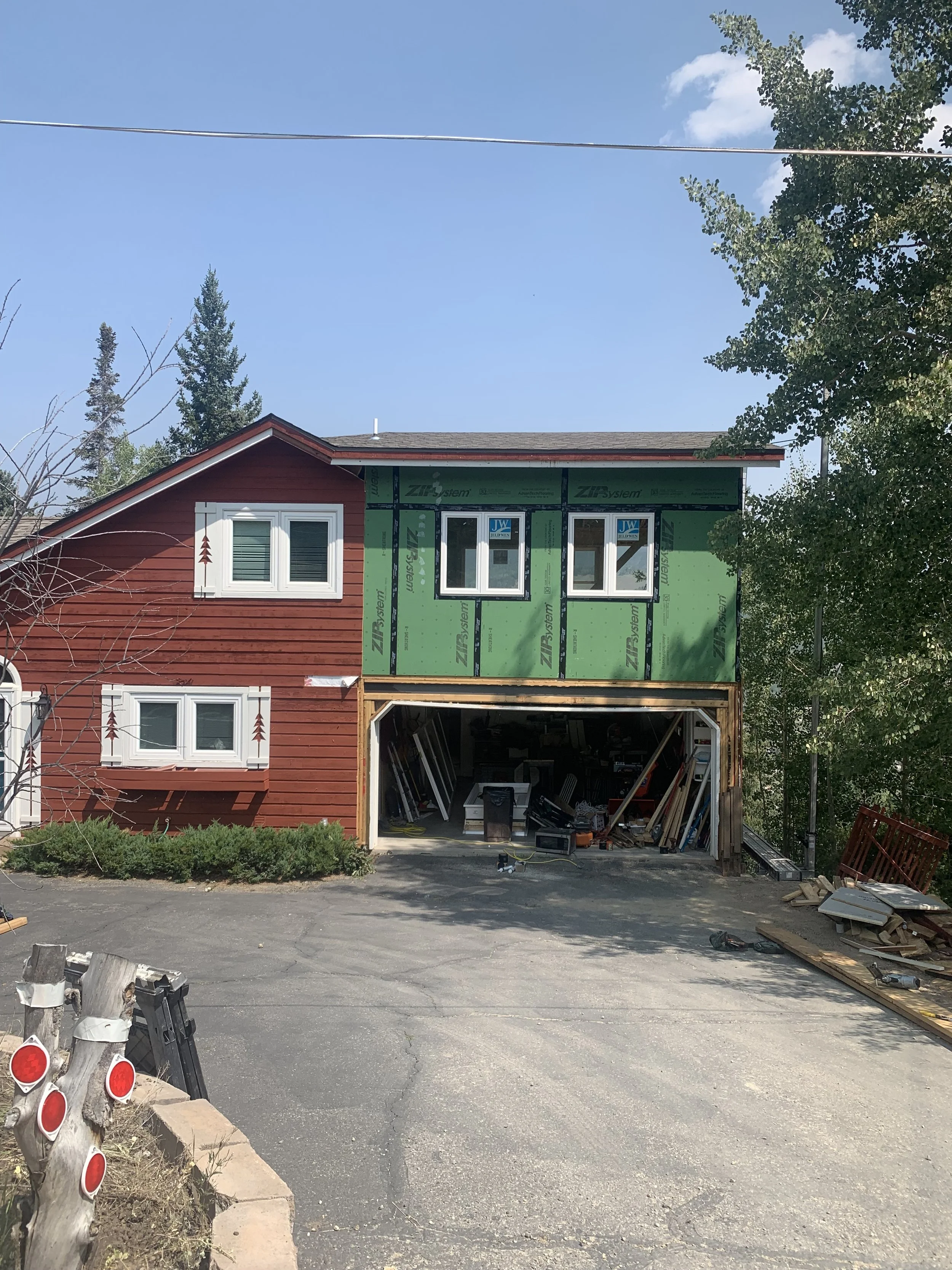 Exterior view of a second-story pop-top renovation in Silverthorne, Colorado, showing an upper-level addition framed and sheathed above an existing garage during a mountain home renovation by Prenvalley Builders.