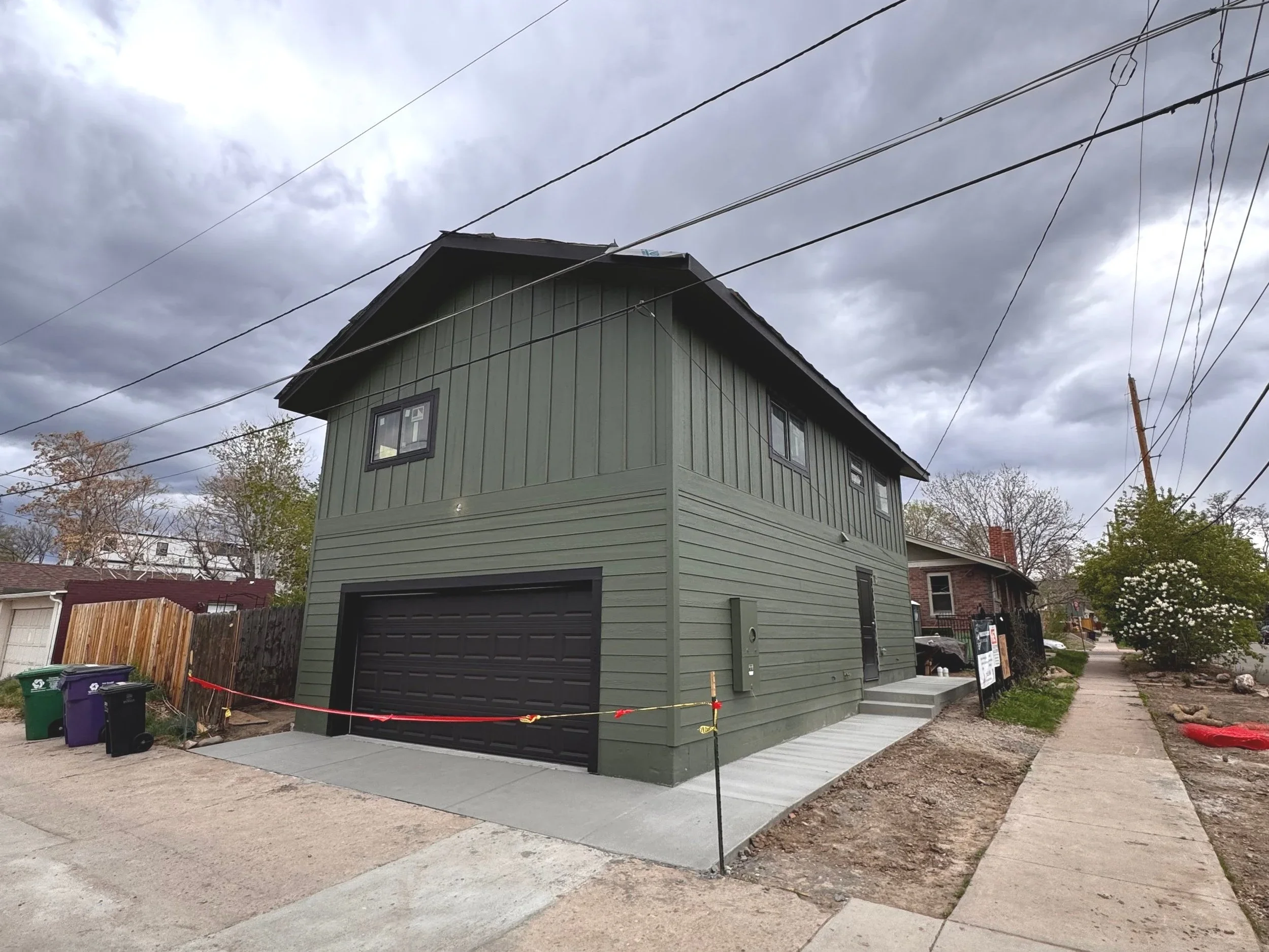 Exterior view of a two-story design-build ADU in Denver featuring green vertical and horizontal siding, integrated garage, and compact urban footprint by Prenvalley Builders