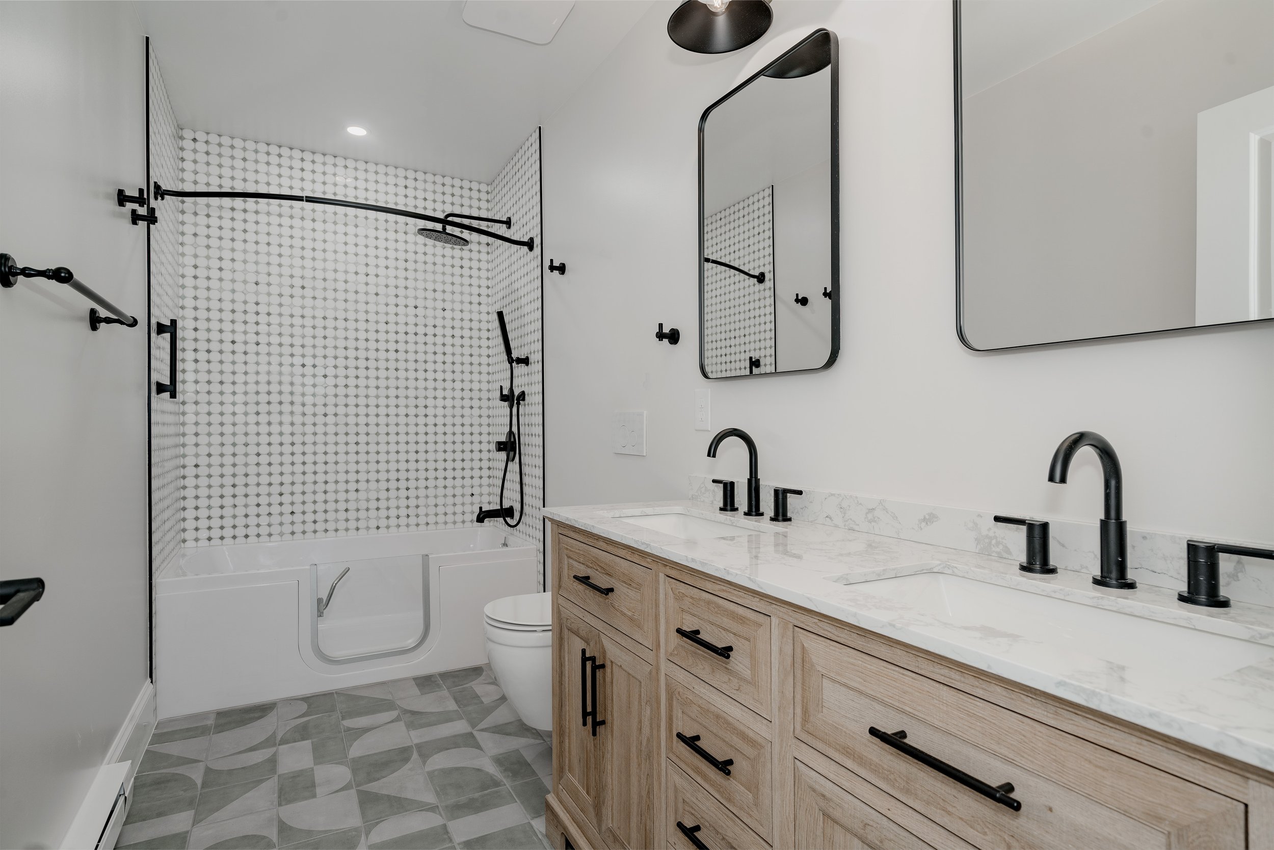 Bathroom interior of a garage-to-ADU conversion in Denver, Colorado, featuring an accessible tub, tiled shower surround, double vanity, and durable finishes installed by Prenvalley Builders.