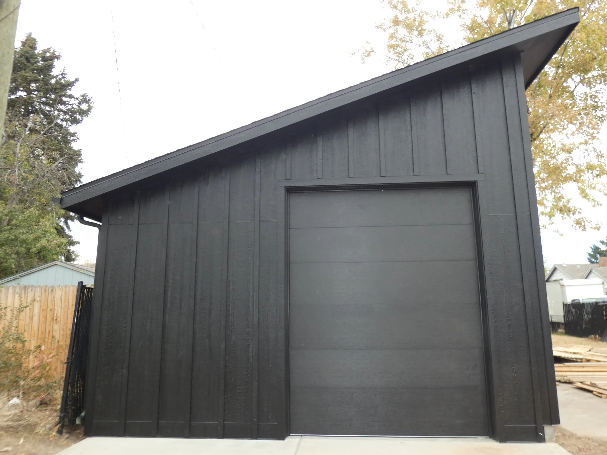 Exterior view of a custom detached garage in Denver’s Barnum neighborhood, featuring a tall overhead garage door and a single-slope roof for large vehicle access.