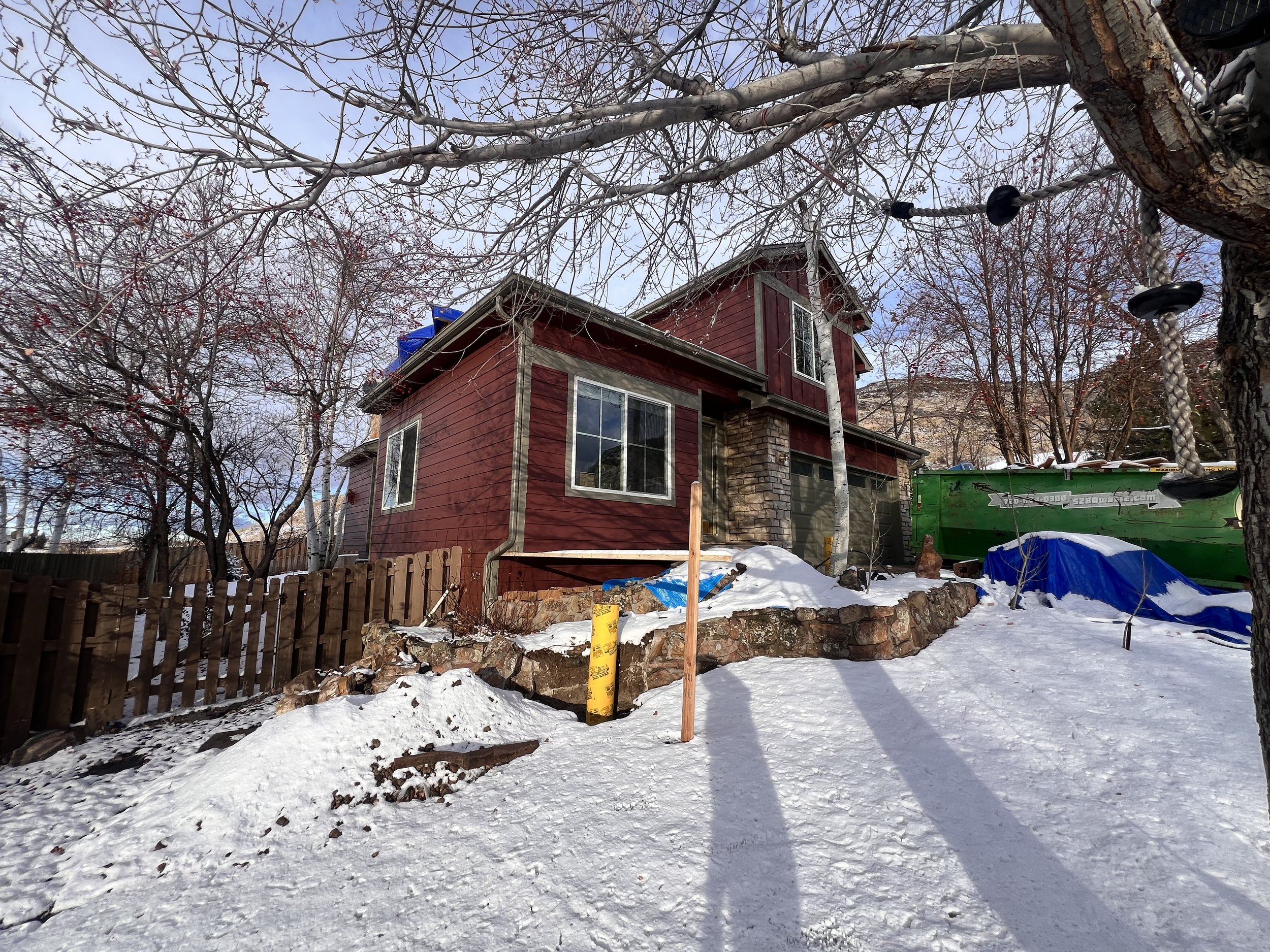 Rear exterior view of a pop-top renovation in Golden, Colorado, photographed during winter construction conditions with a partial second-story addition in progress.