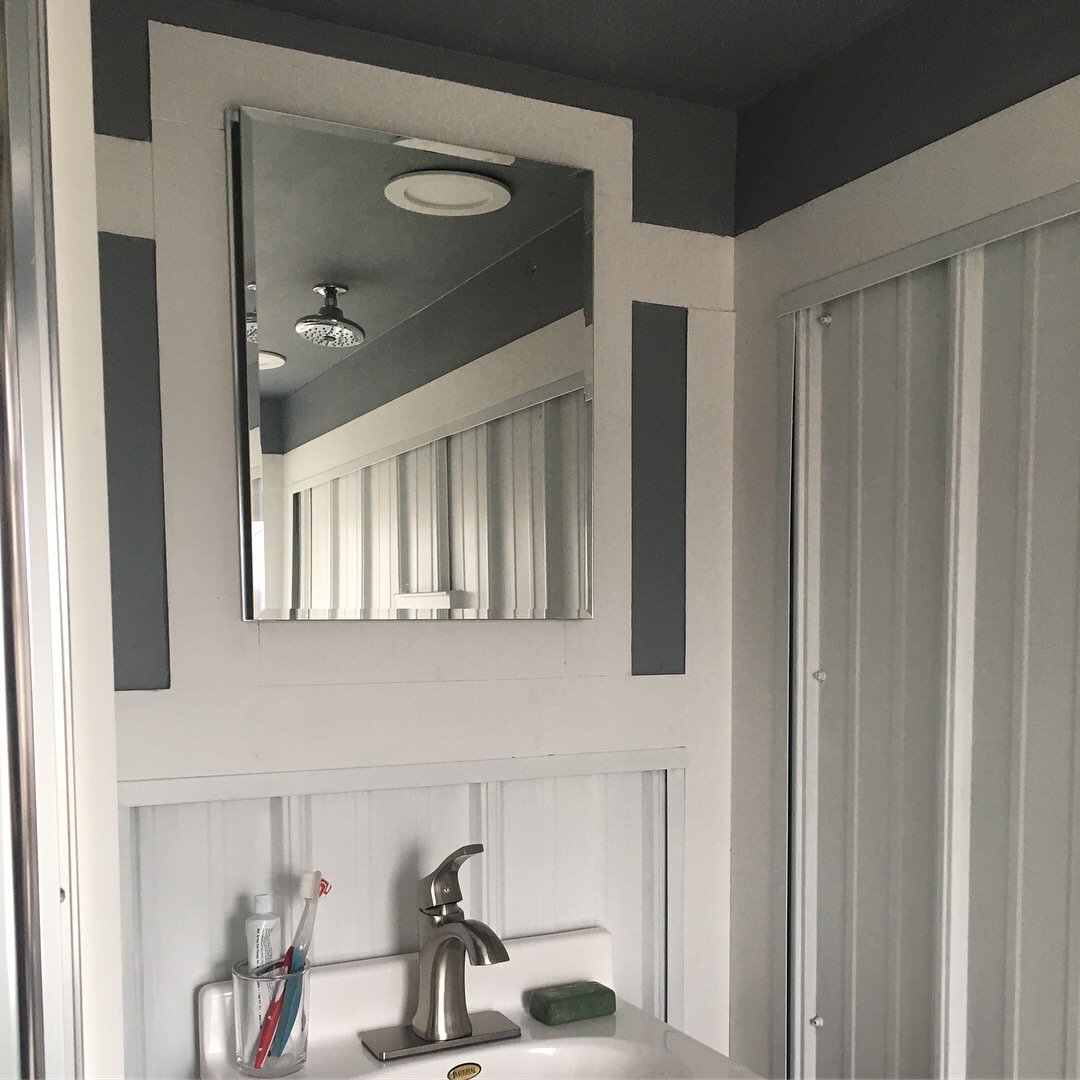 Compact bathroom vanity inside a custom mobile tiny home by Prenvalley Builders featuring durable wall panels, integrated mirror, and space-efficient fixtures.