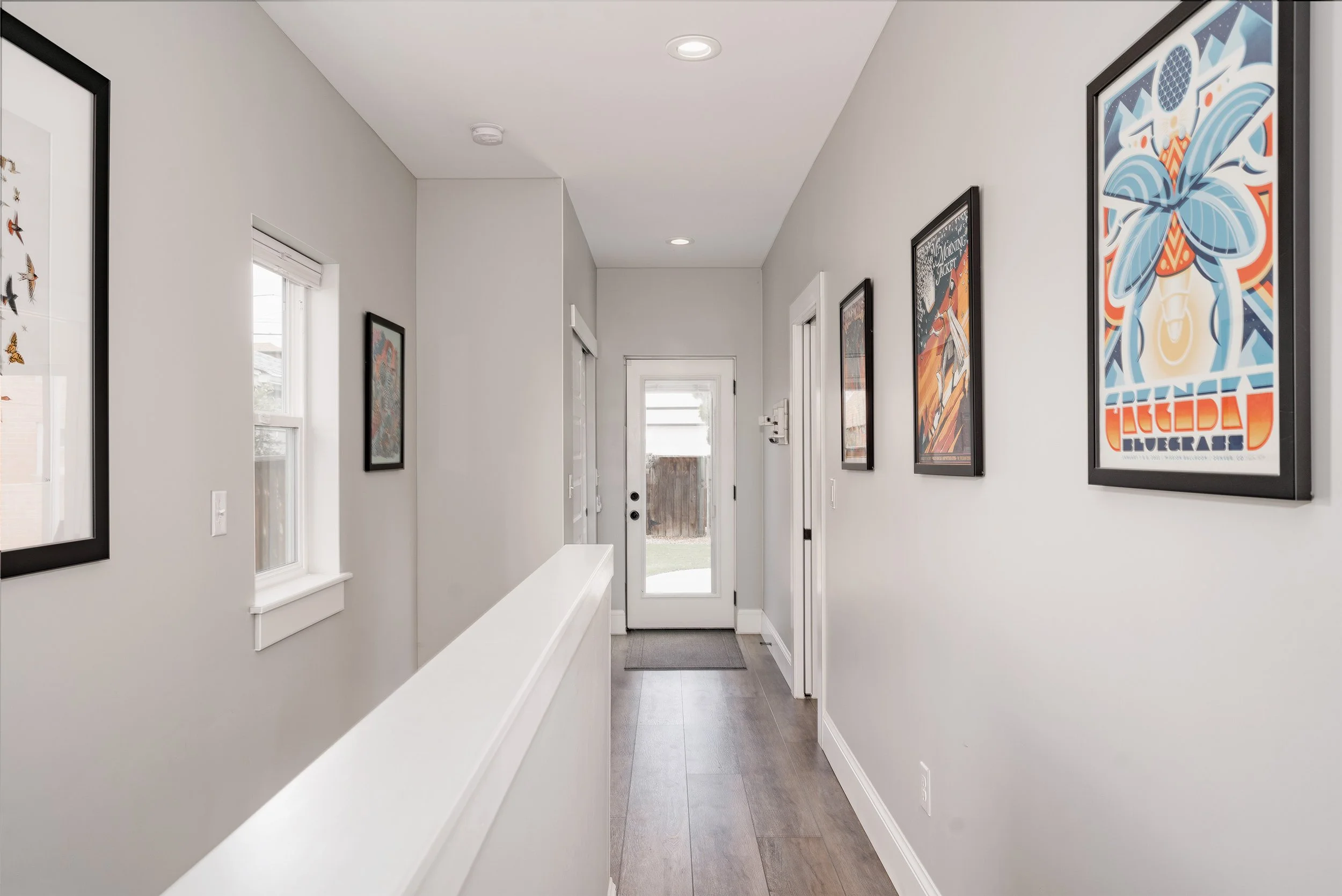 Interior hallway of a Denver home addition leading to a new primary suite, featuring recessed lighting, wood flooring, and clean modern finishes built by Prenvalley Builders.