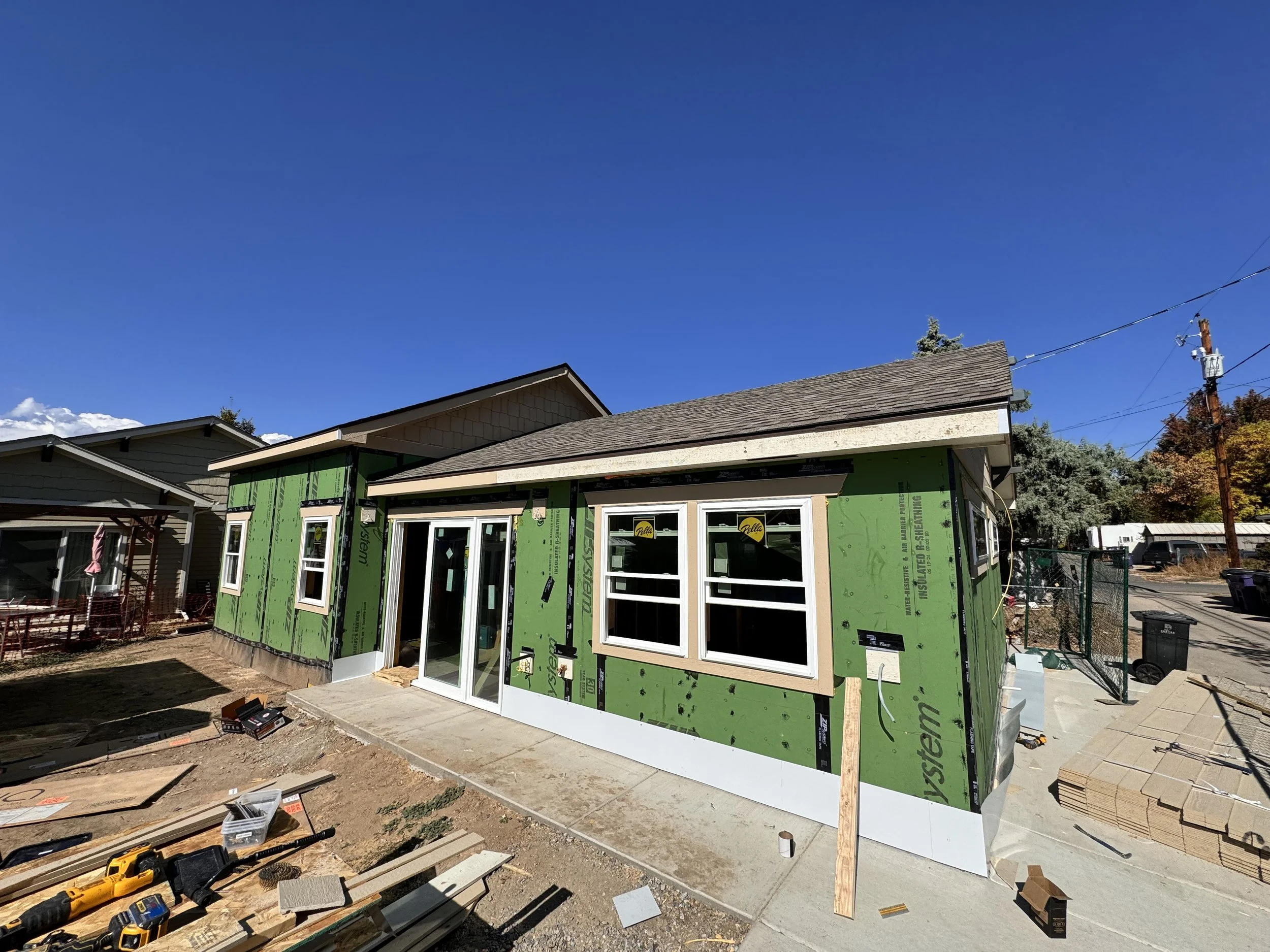 Garage-to-ADU conversion under construction in Denver, Colorado, showing exterior framing completion, window installation, weather barrier, and patio slab executed by Prenvalley Builders.