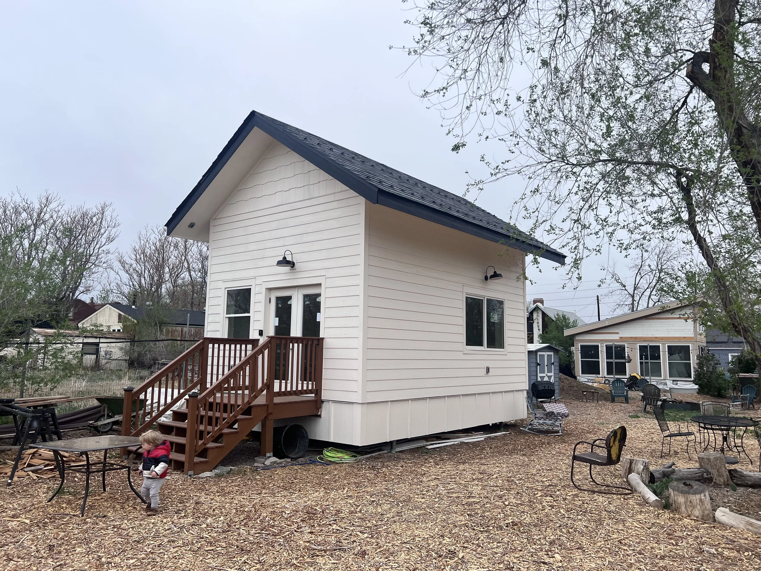Completed exterior of a detached accessory dwelling unit in Denver, Colorado, built by Prenvalley Builders, featuring white horizontal siding, a pitched roof, and an elevated entry with wood stairs.