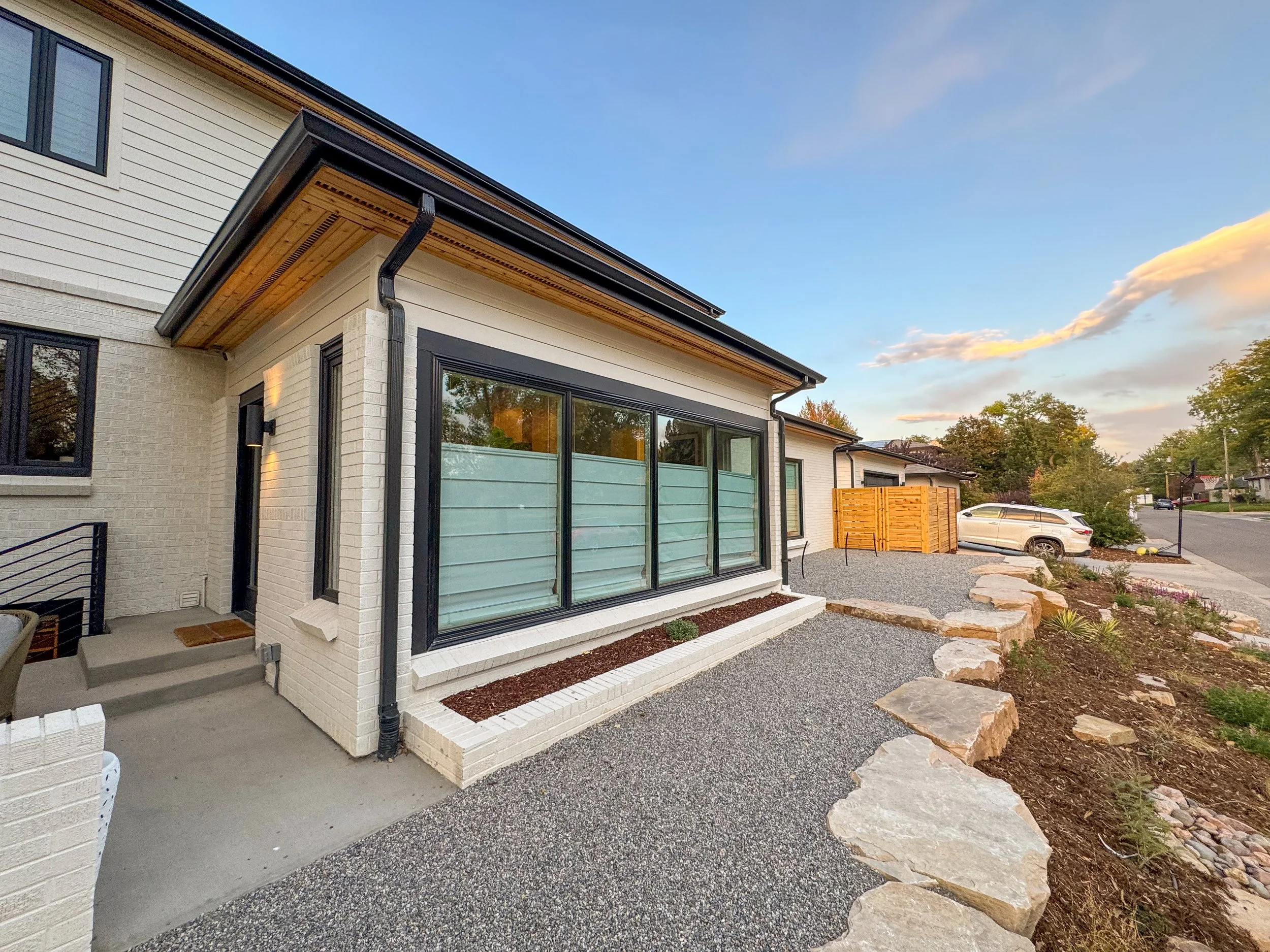 Side exterior of a Denver pop-top renovation featuring updated windows, brickwork, and coordinated exterior detailing