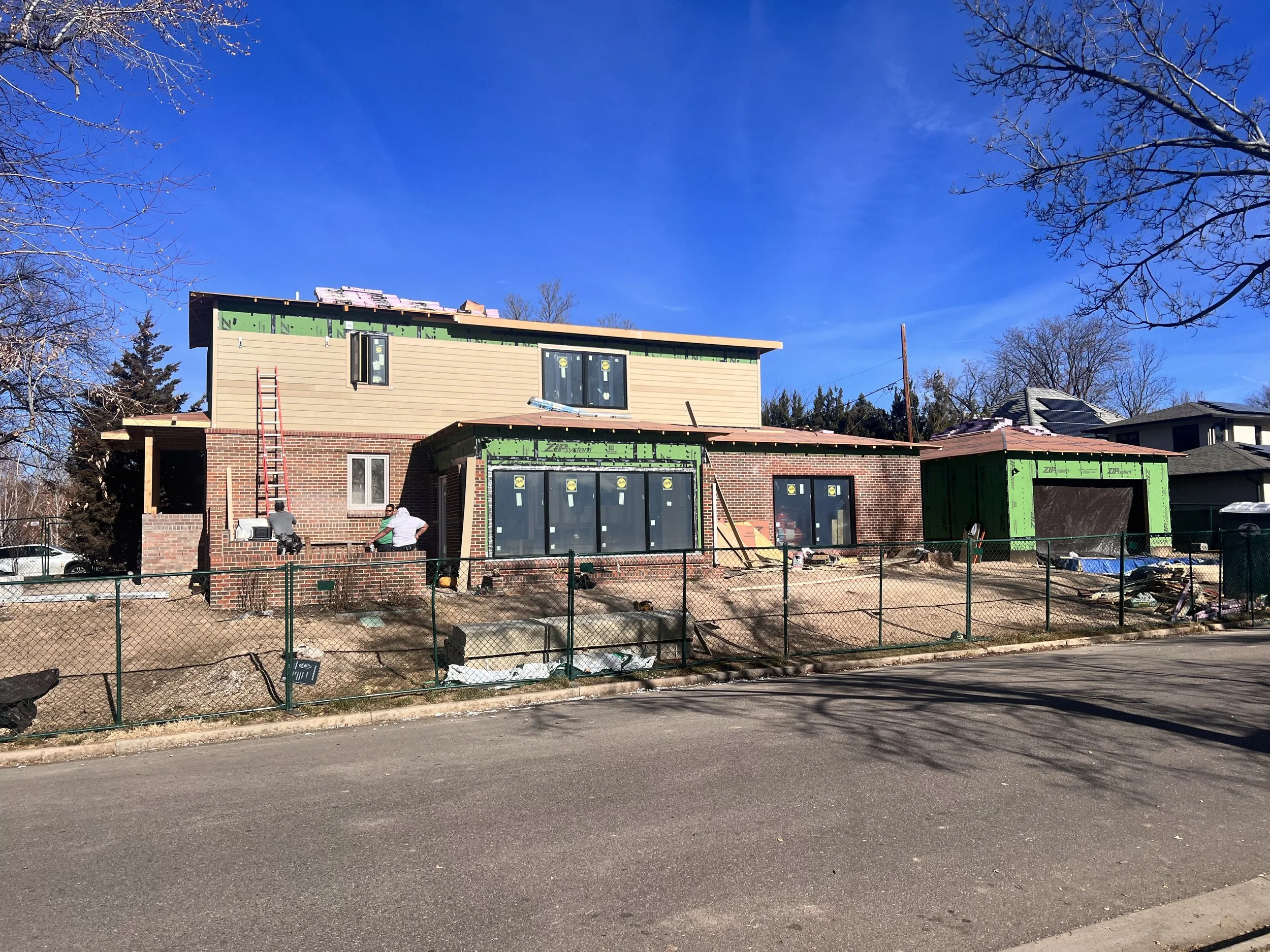 Denver pop-top renovation during exterior siding and window installation, showing second-story addition and rear expansion under construction