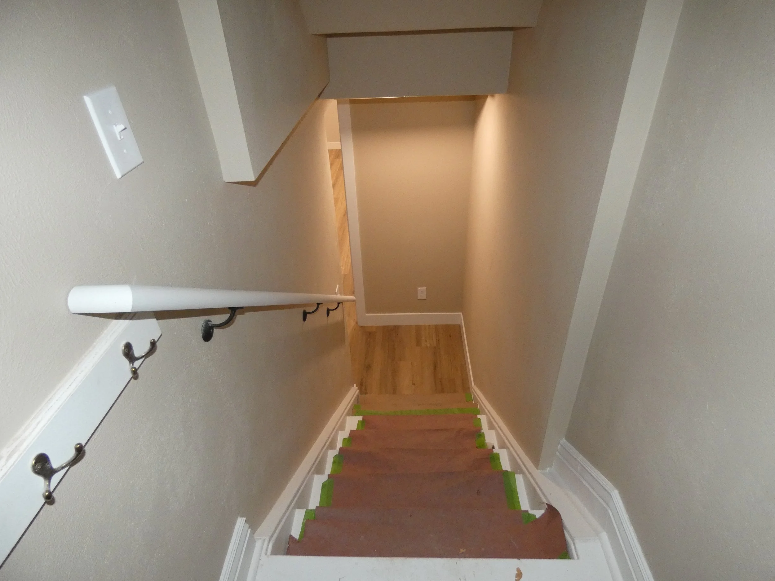 Stairwell access to a lower-level ADU built during a Denver basement renovation, featuring updated finishes, handrails, and improved circulation by Prenvalley Builders.