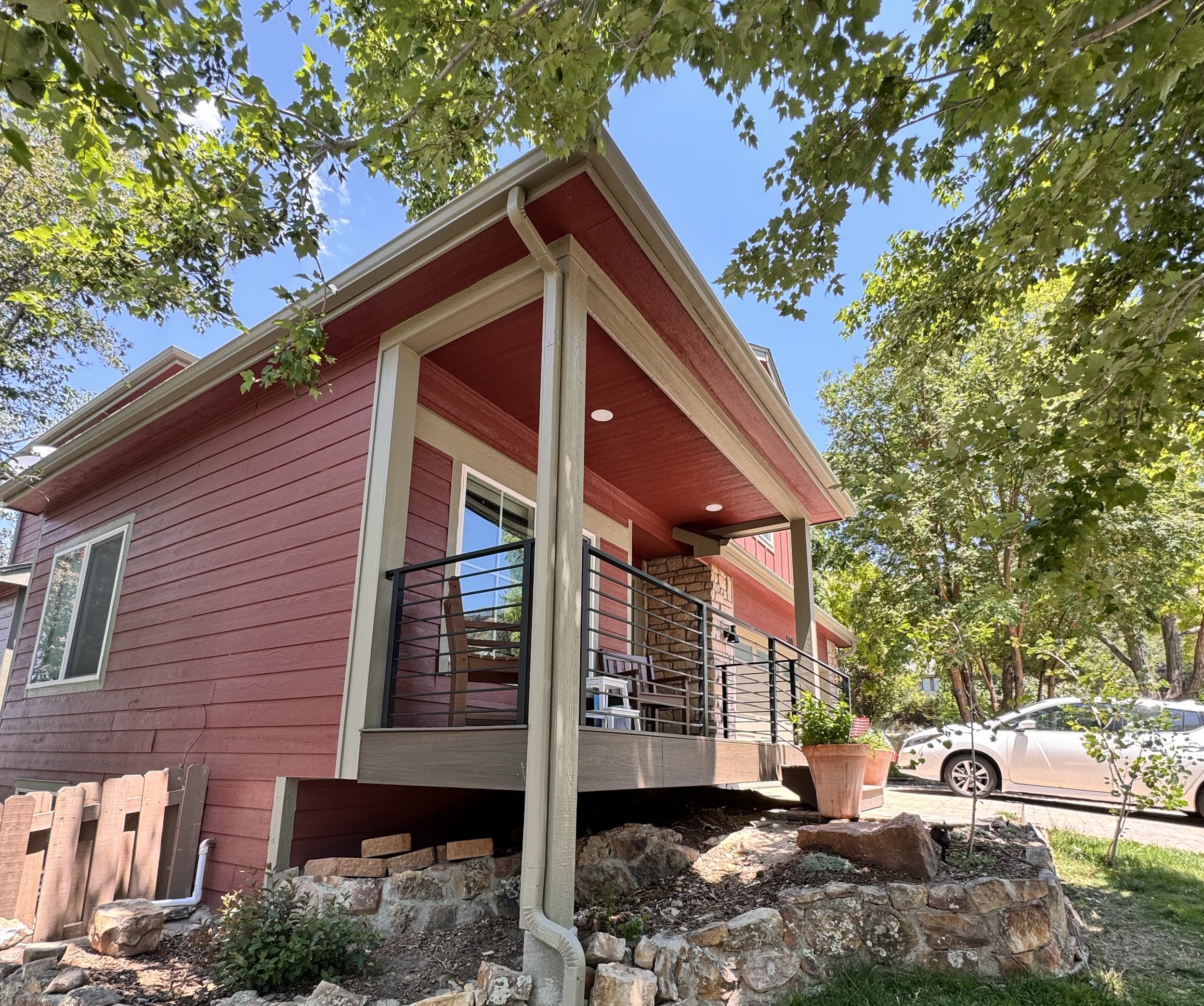 Side elevation of a completed covered front porch as part of a pop-top renovation in Golden, Colorado, showing railing details and site integration.