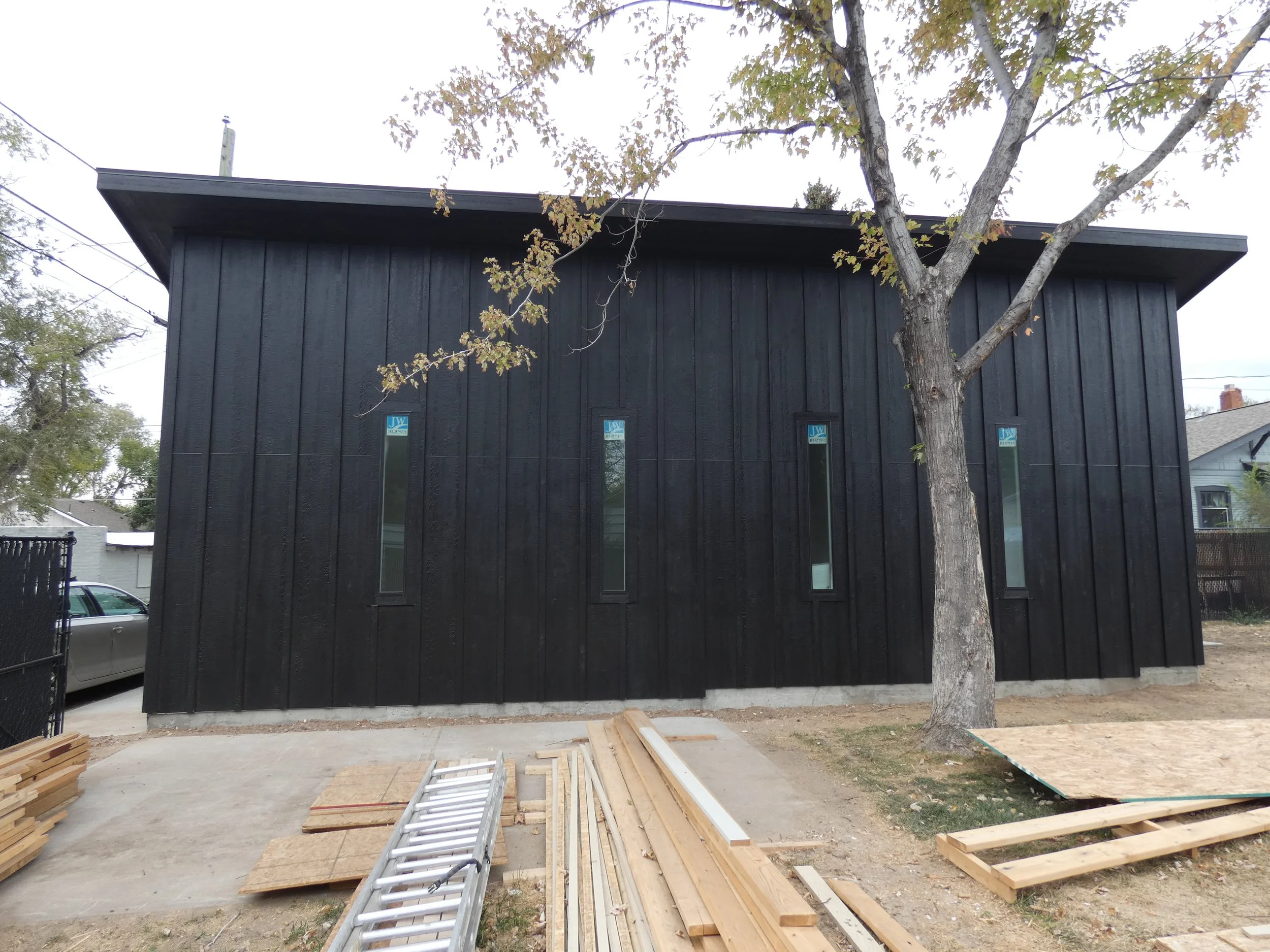 Finished exterior of a custom detached garage in Denver’s Barnum neighborhood, featuring black vertical siding, narrow windows, and a clean modern profile.
