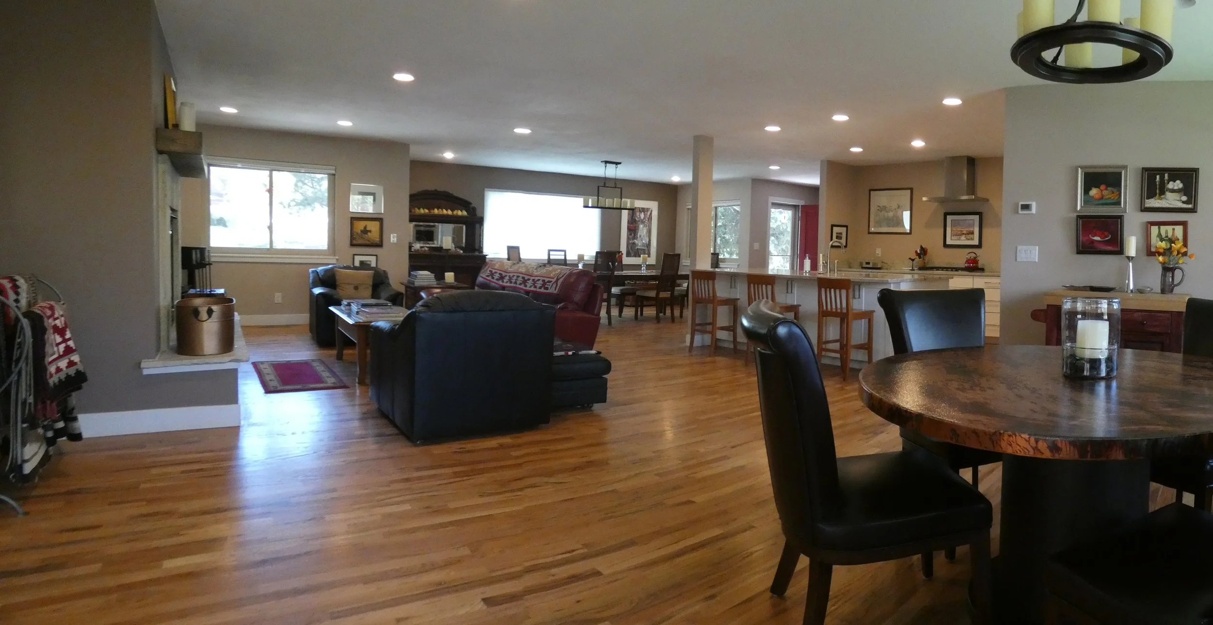 Alternate view of a completed open-concept interior in a Denver home renovation, showing hardwood floors, recessed lighting, and connected living, dining, and kitchen spaces built by Prenvalley Builders.