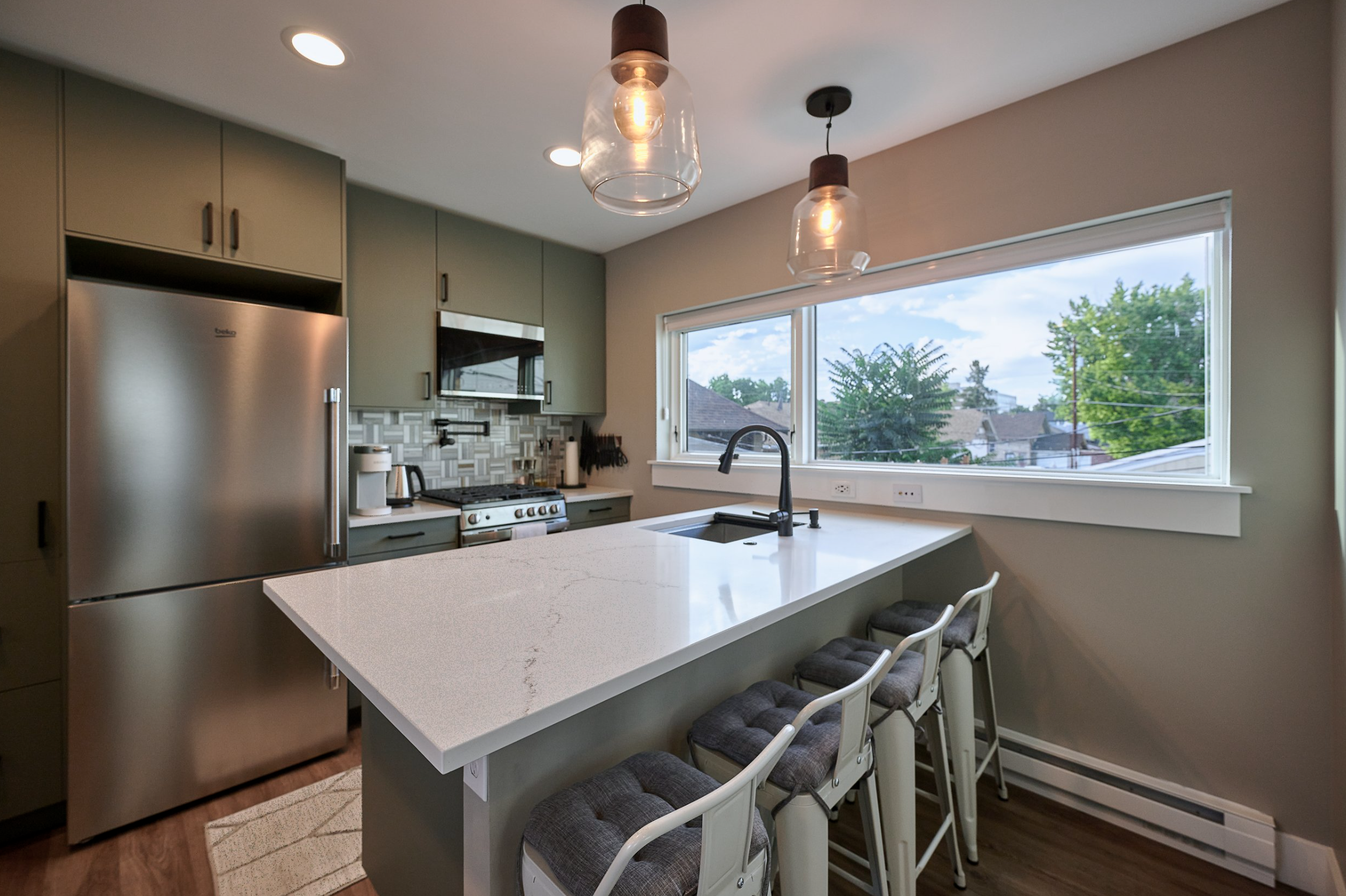 Interior kitchen of a Denver accessory dwelling unit featuring a quartz island, modern cabinetry, stainless steel appliances, and efficient layout built by Prenvalley Builders.