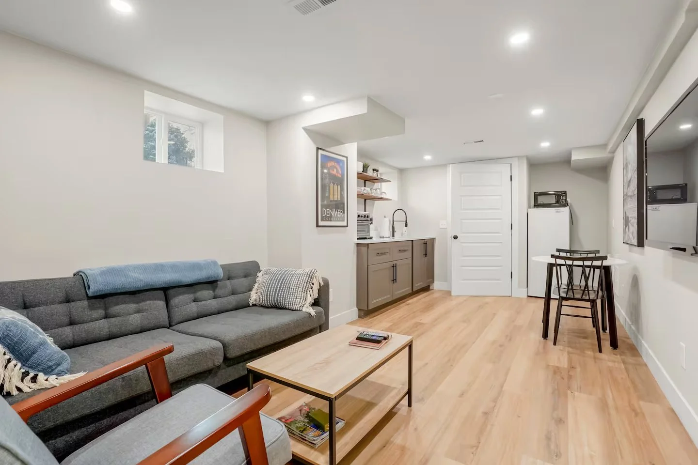 Open living area and kitchenette within a lower-level ADU built during a Denver basement renovation, featuring new flooring, lighting, and cabinetry by Prenvalley Builders.