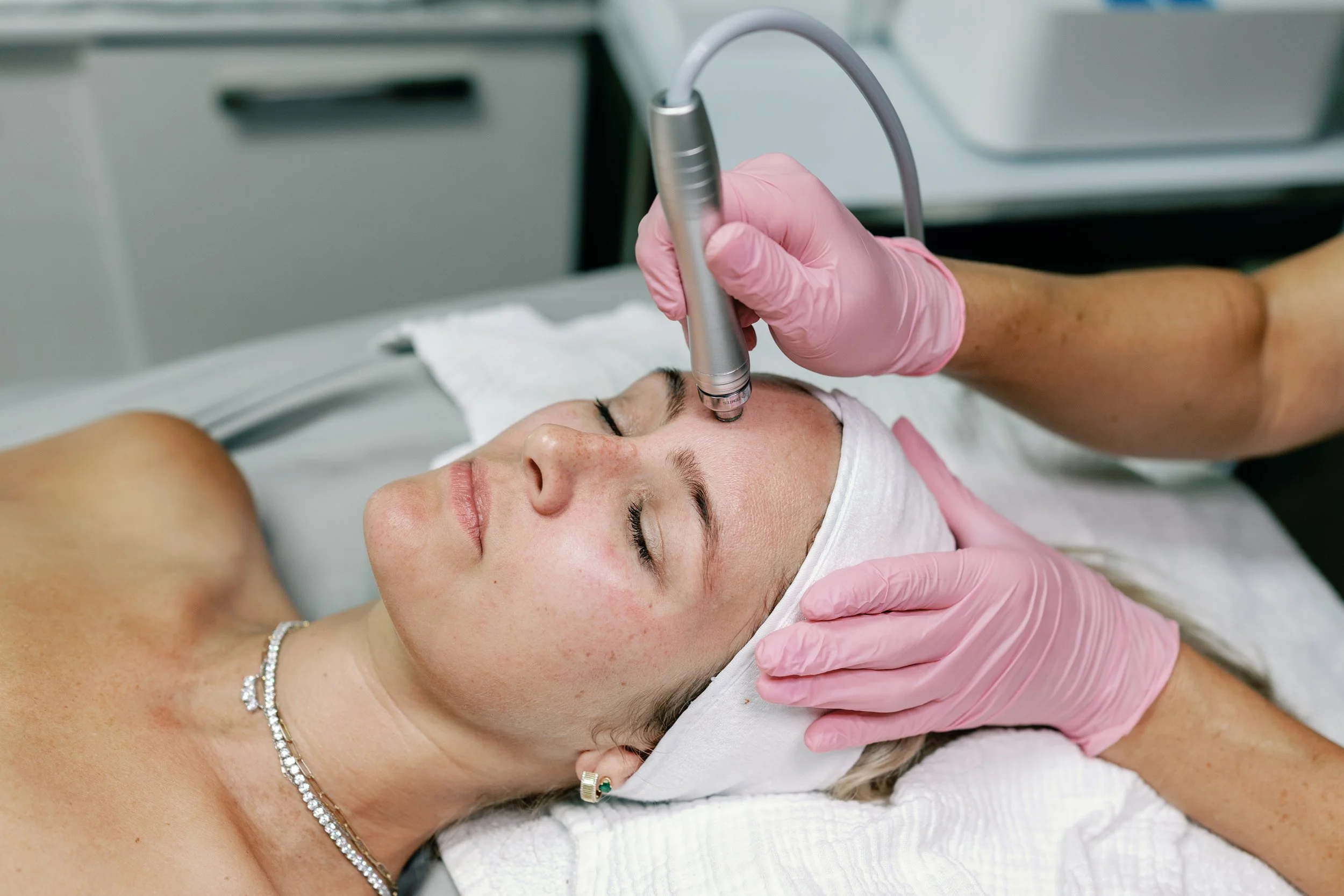 An esthetician uses a HydroDiamond dermabrasion wand device tool on a woman's forehead during a facial at Moonstone Skin & Body Care in Novato, California