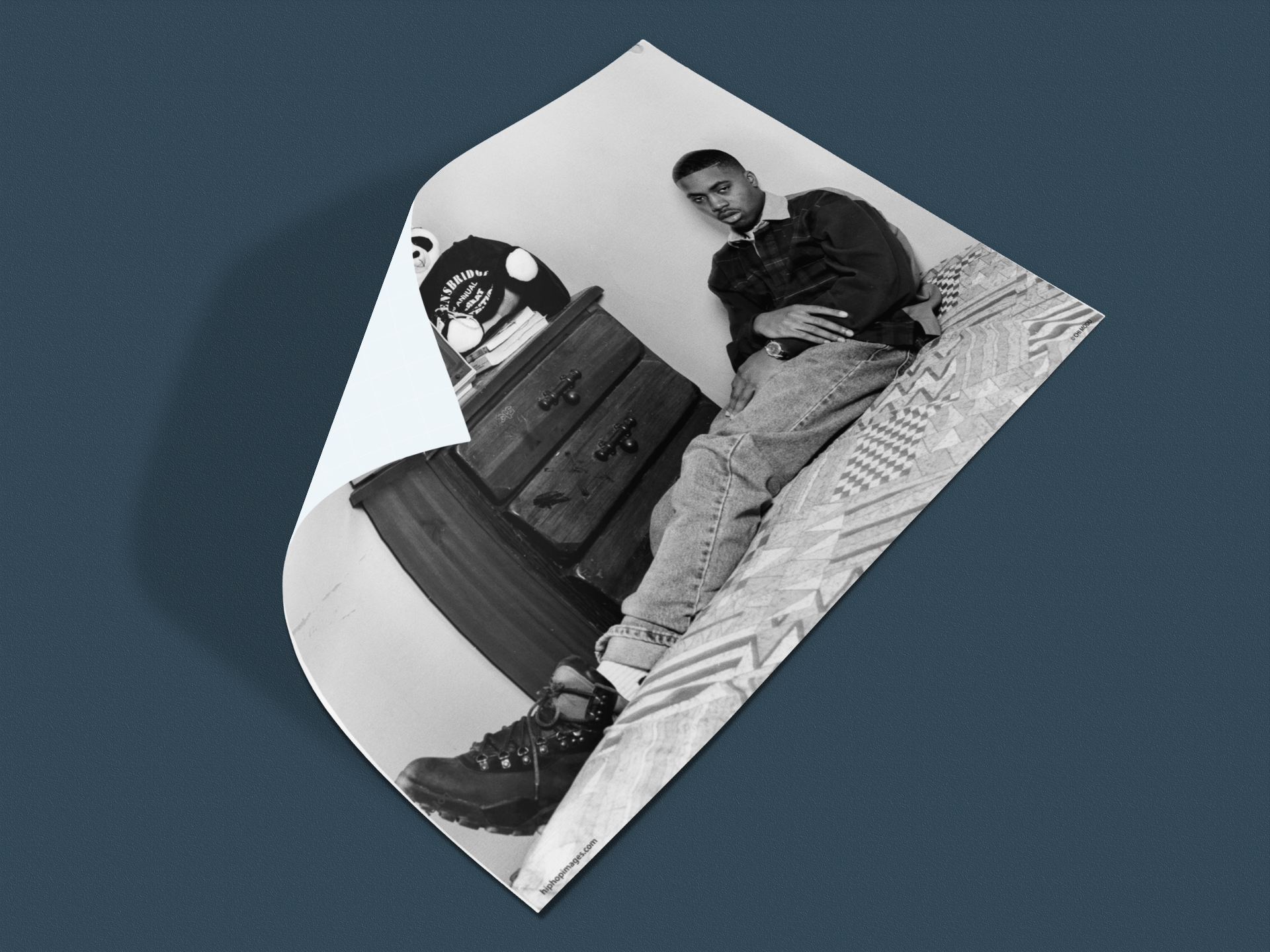 Black-and-white portrait of Nas sitting against wall, photographed by Chi Modu® during 90s hip-hop