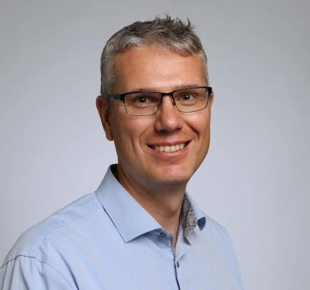 Mann smiler i blå skjorte