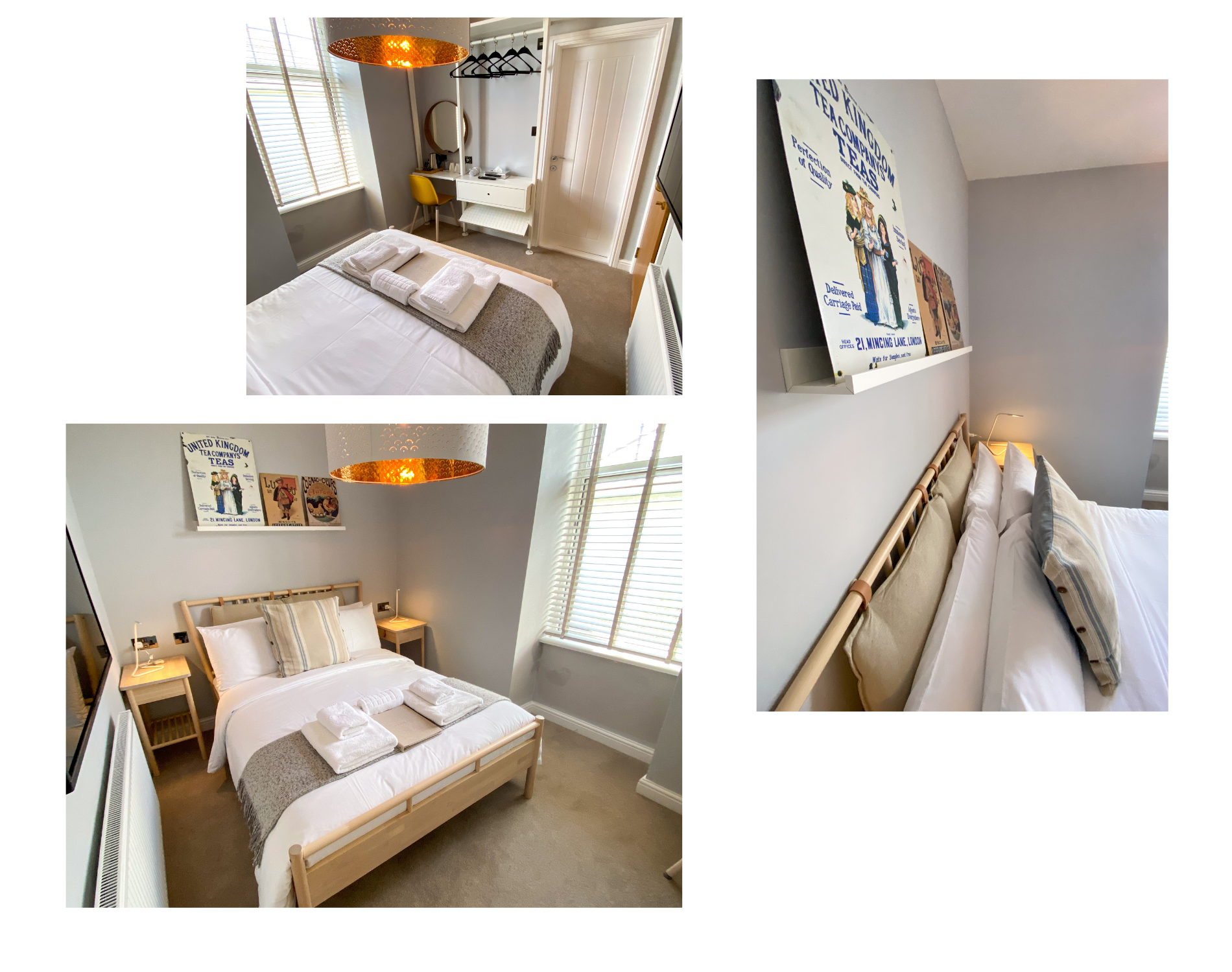 A cozy bedroom with a wooden bed frame, white bedding, and folded towels. The room has two bedside tables with lamps, a large window with blinds, and framed vintage posters on the walls. A desk with a yellow chair and a mirror is near the door, with a hanging copper light fixture overhead.