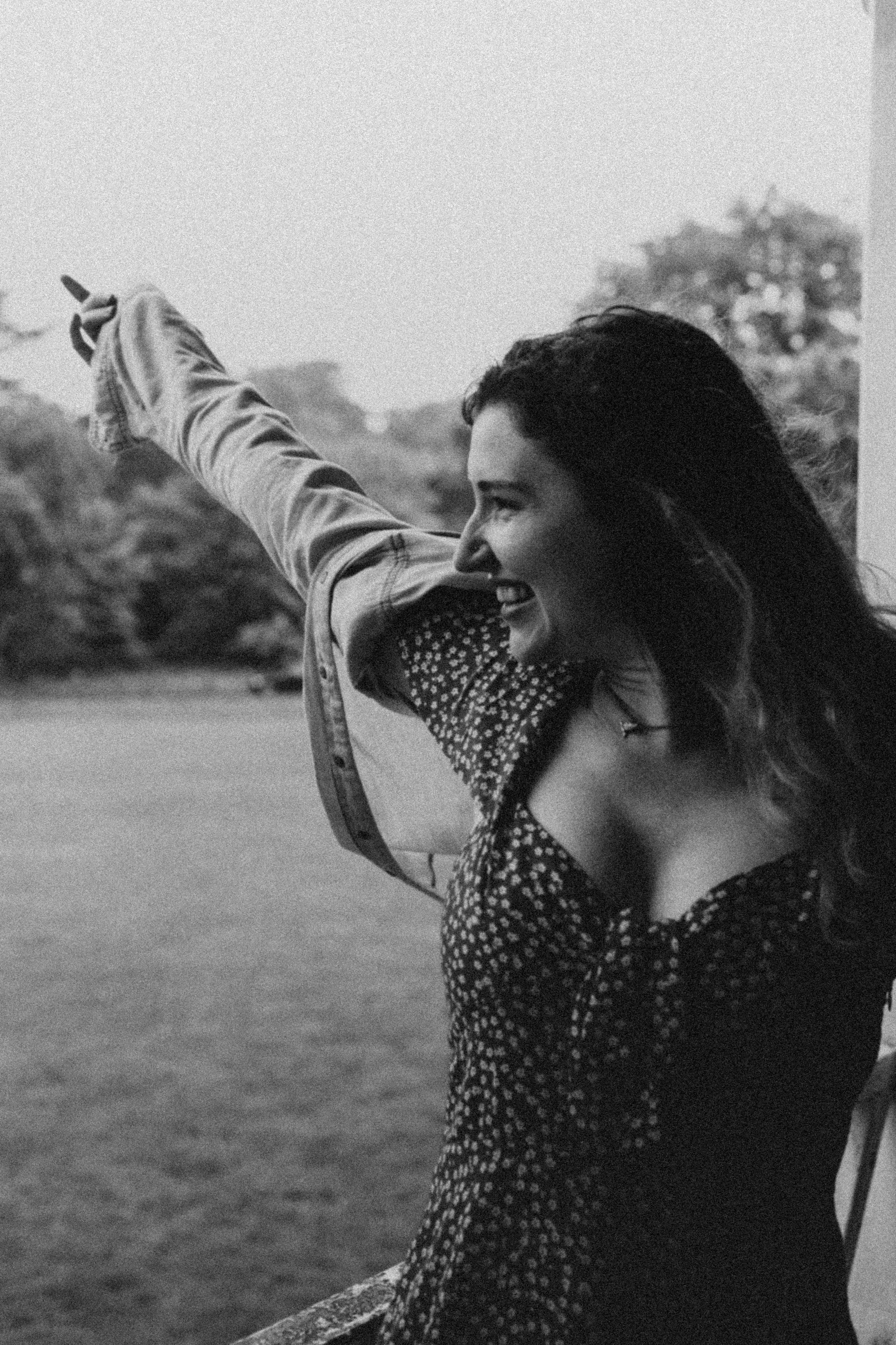 Black and white portrait of a woman with her hands in the air looking joyful in a natural environment on Mousehold Heath Norwich Norfolk 