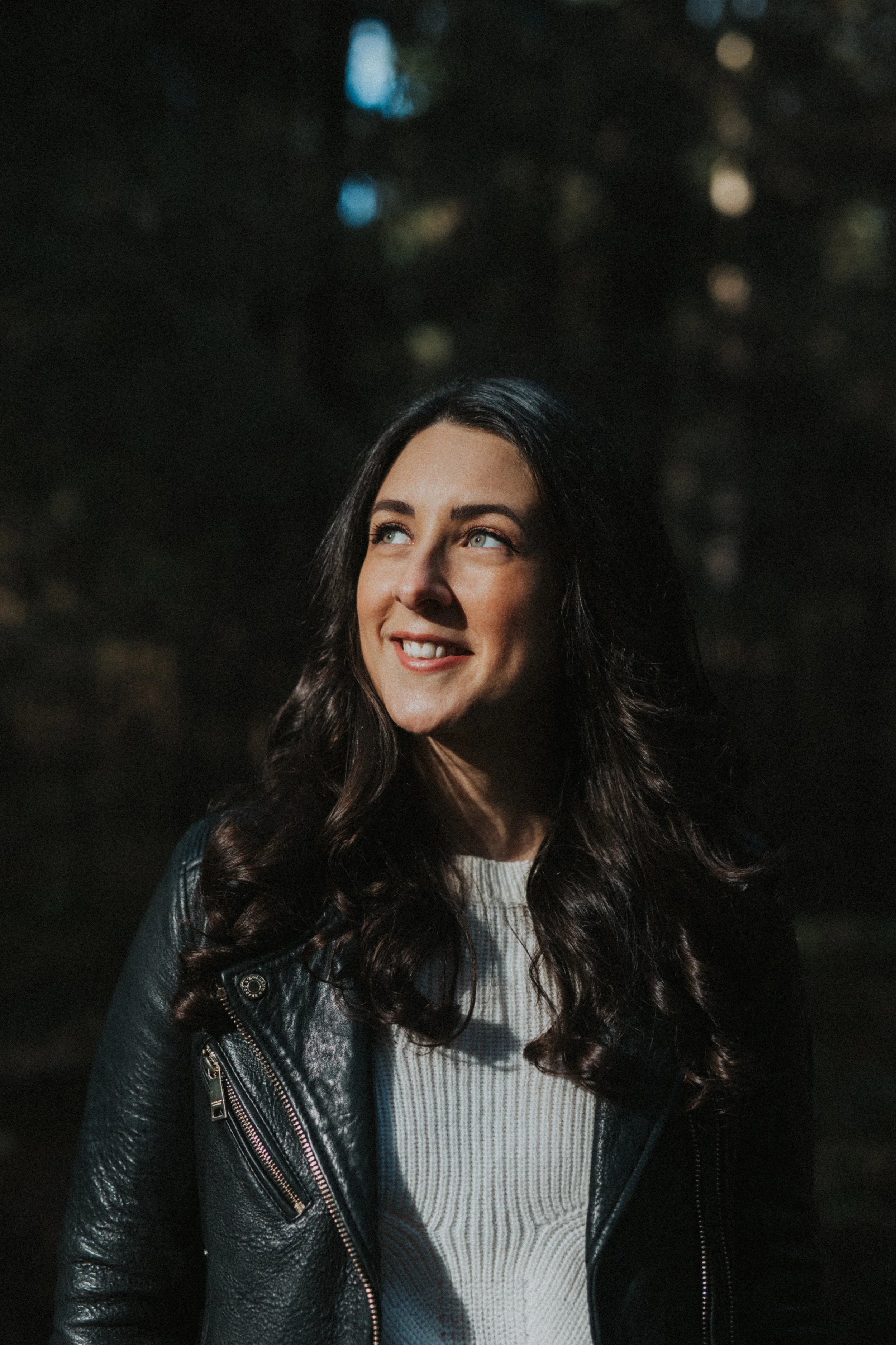 Woman in dark forest surrounds with her face towards the bright sun in Thetford Forrest Suffolk 