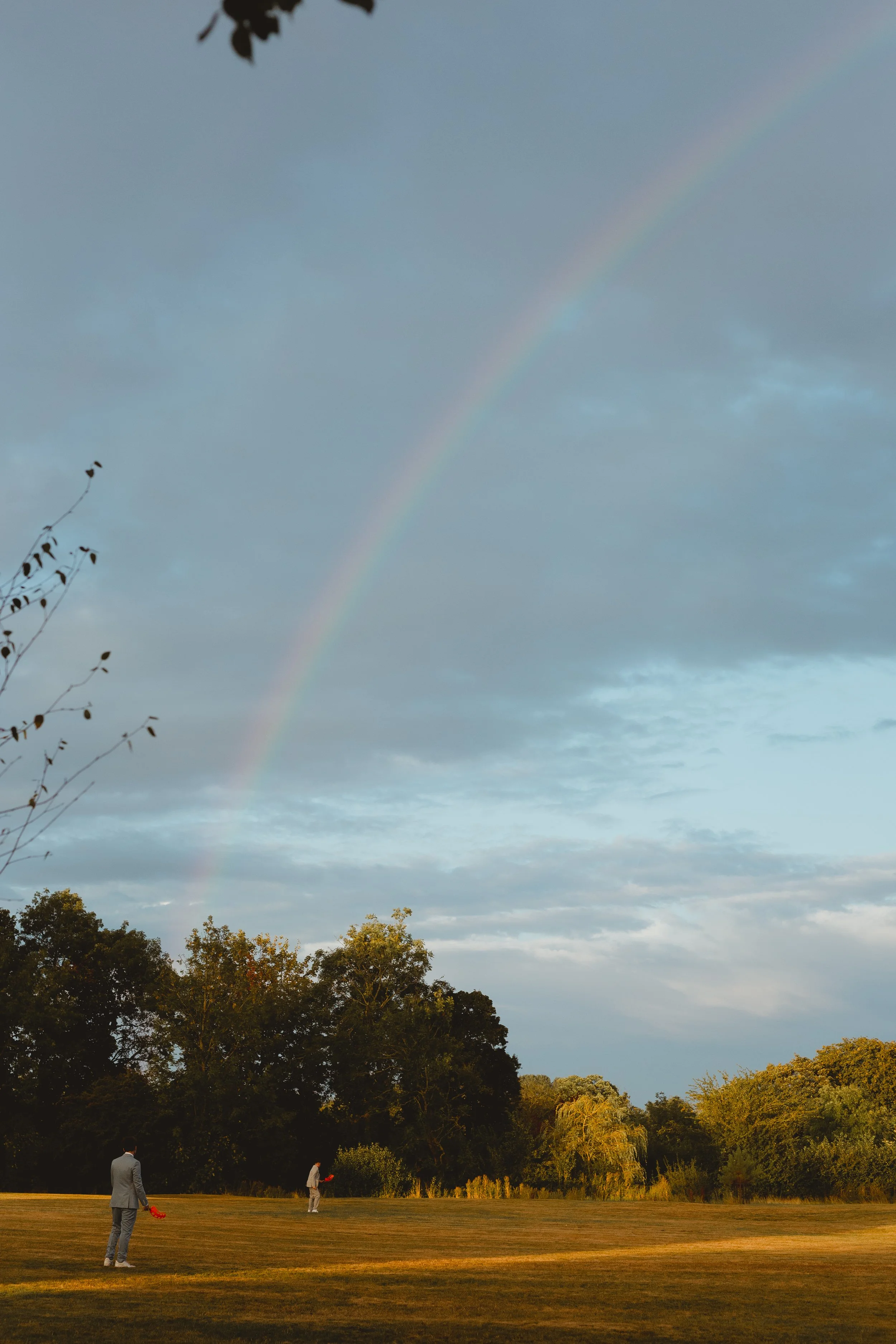beautiful blue sky with rainbow with two children playing cricket in the afternoon sun Suffolk Barn Hawstead Bury St. Edmunds 