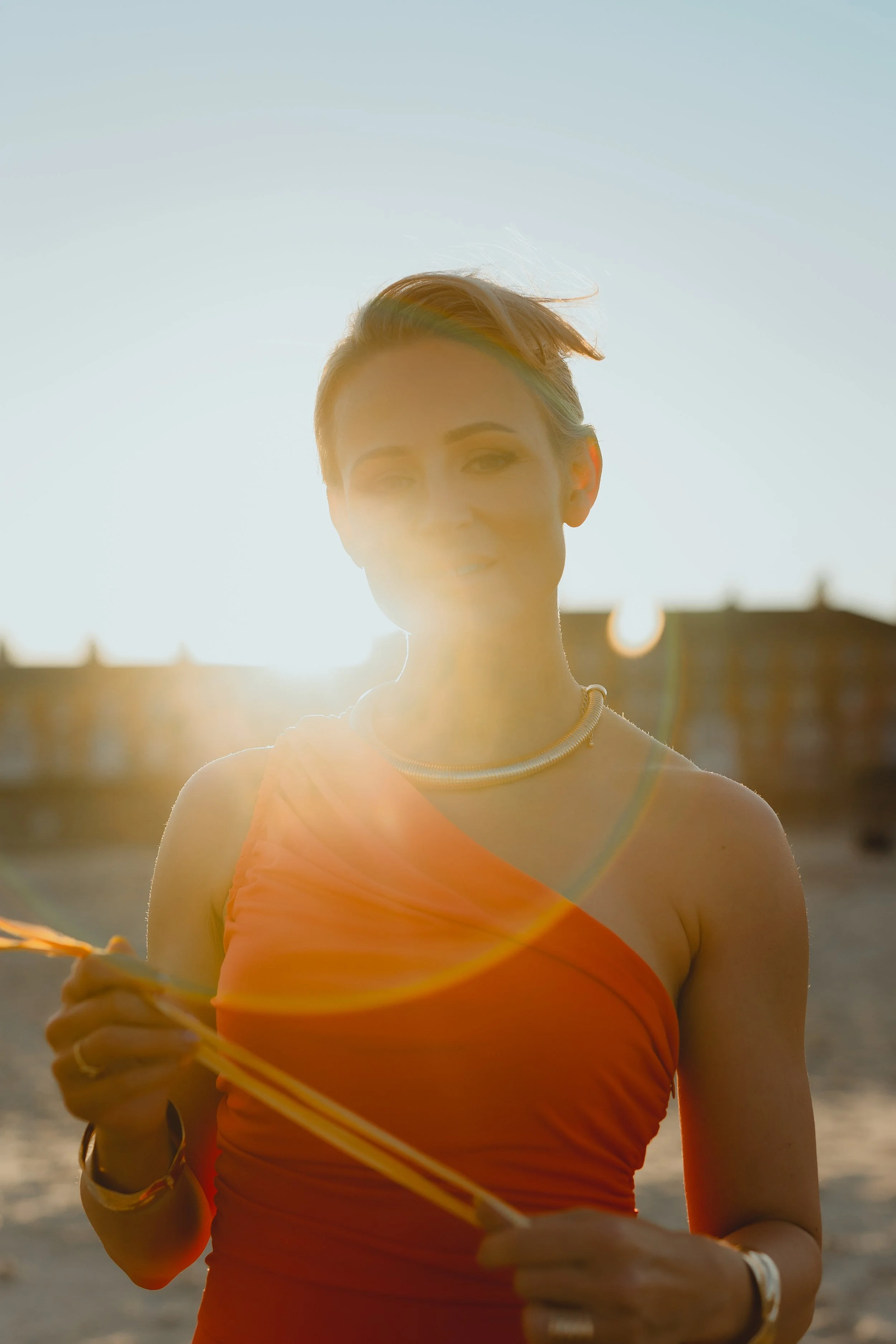 Golden hour backlit portrait of an attractive blonde woman in an orange jumpsuit on Lowestoft Suffolk seafront 