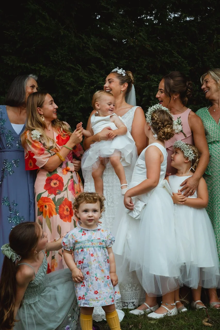 Editorial image of bustling multi-generational family at a wedding reception with the bride and flower girls in the centre in vibrant outfits with flowers at Georgian Townhouse Norwich Norfolk 