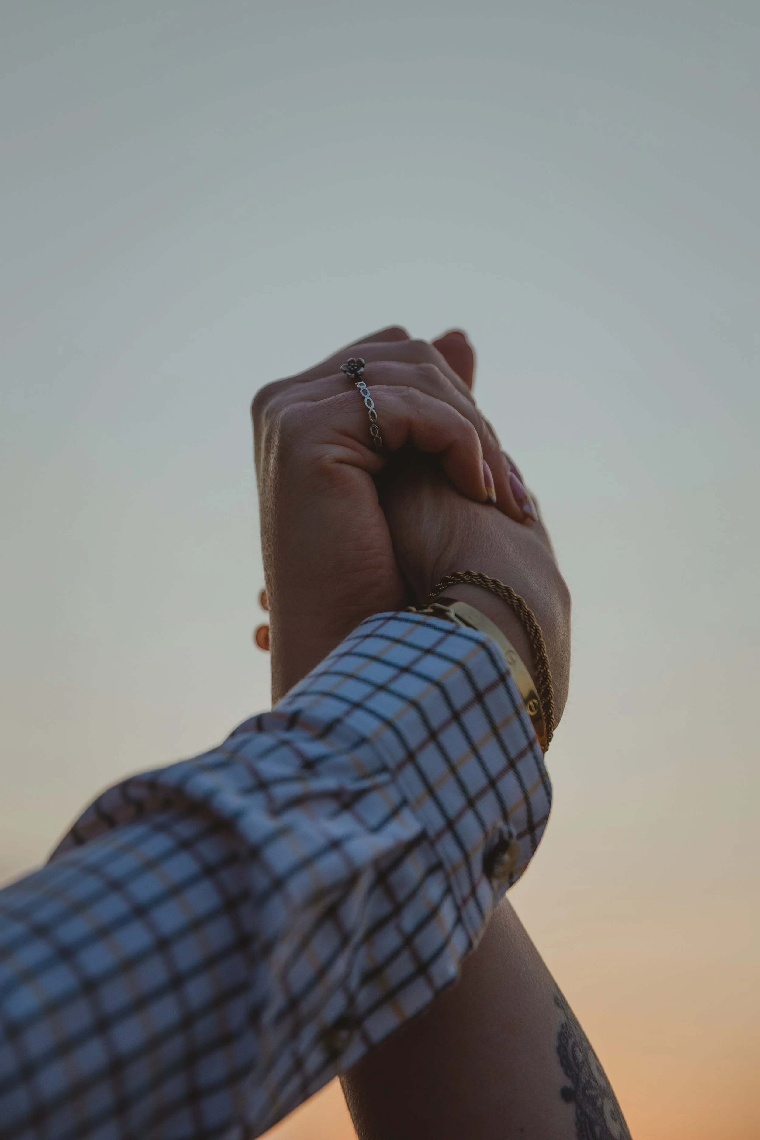 Two woman's hands clasp together against a soft twilight sky at Carlton Marshes Lowestoft Suffolk 