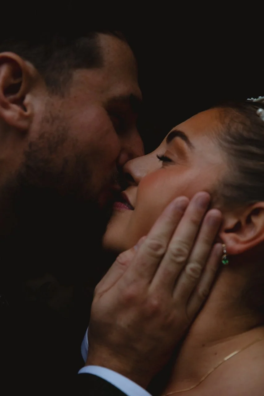 An intimate close-up of a bride and groom sharing a quiet kiss on their wedding day, captured in a moody, cinematic style in the Plantation Gardens Norwich Norfolk