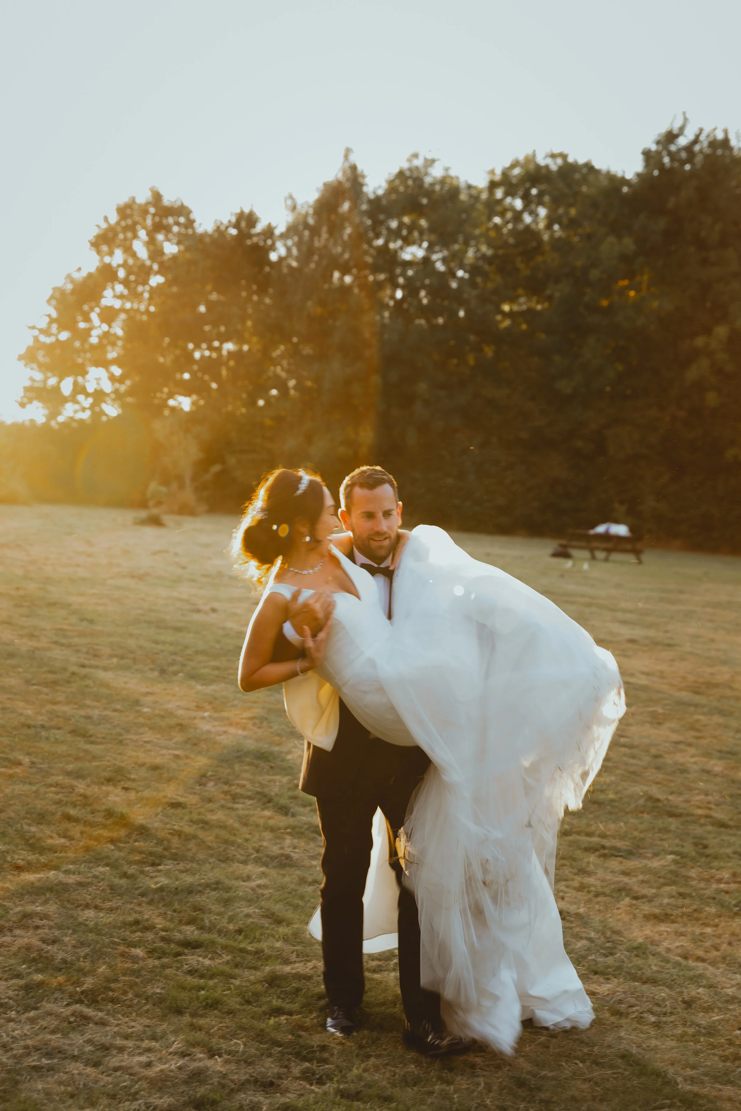 Golden Hour Editorial Sunset Image of groom in tux holding bride in long white dress with tiara backlit sunflare Suffolk 