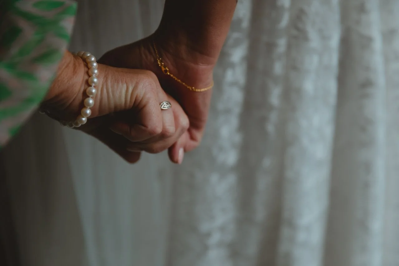 Mother of bride and bride squeeze each others hands in an intimate moody cinematic framing before the bride walks down the aisle Georgian Townhouse Norwich Norfolk