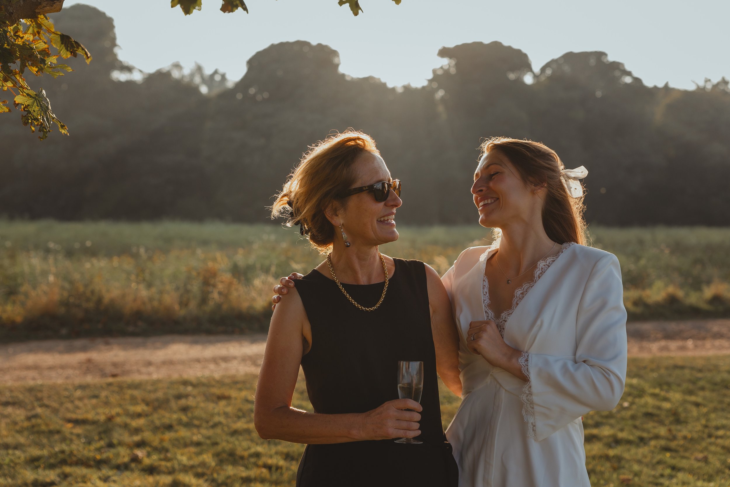 Refined and sophisticated mother of bride and bride looking at each other backlit in the setting sun Sudbourne Hall Orford Suffolk Coast