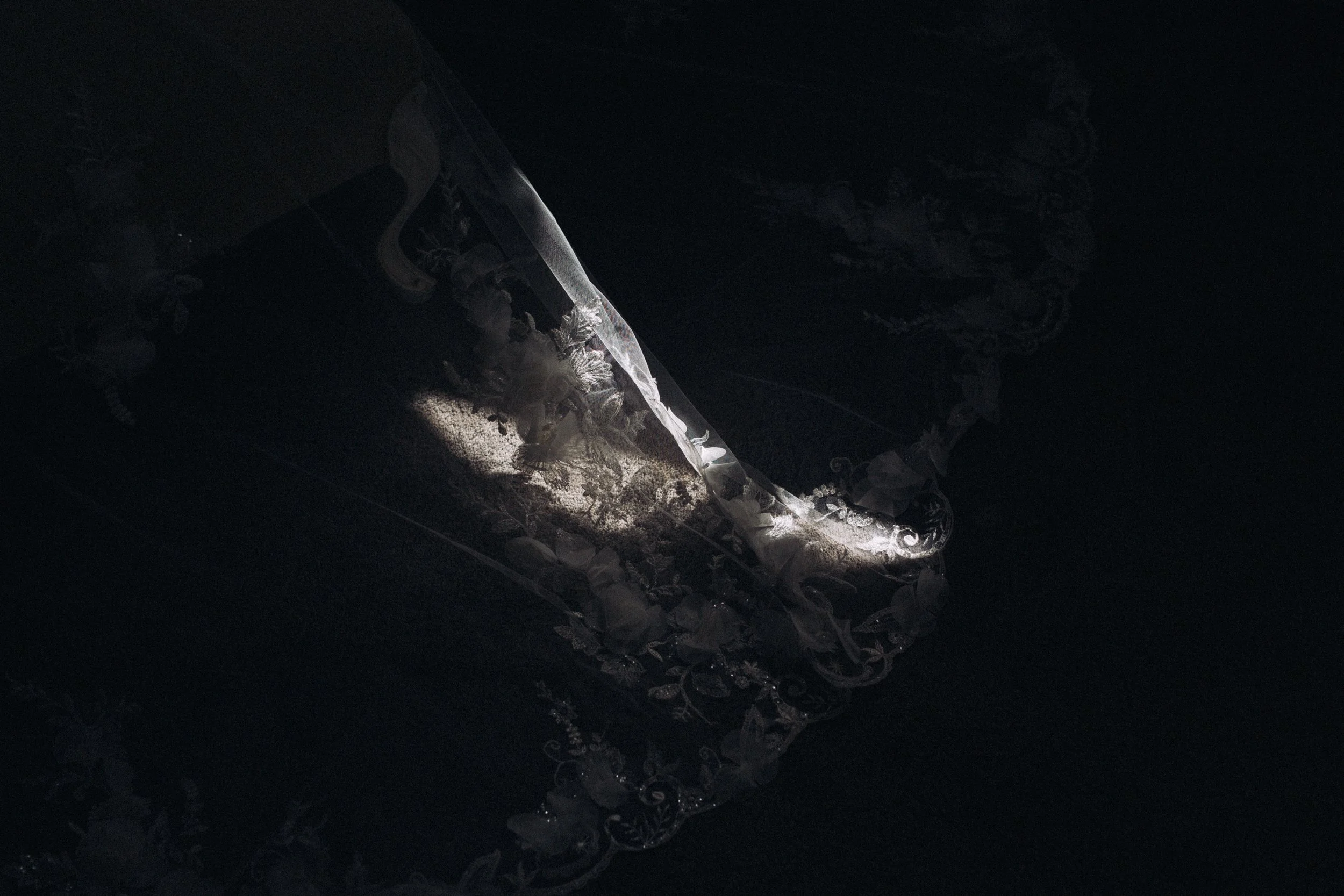 Abstract editorial sunlit image of veil caught in a slice of light against a dark cinematic backdrop at Seckford Hall Hotel and Spa Ipswich Suffolk 