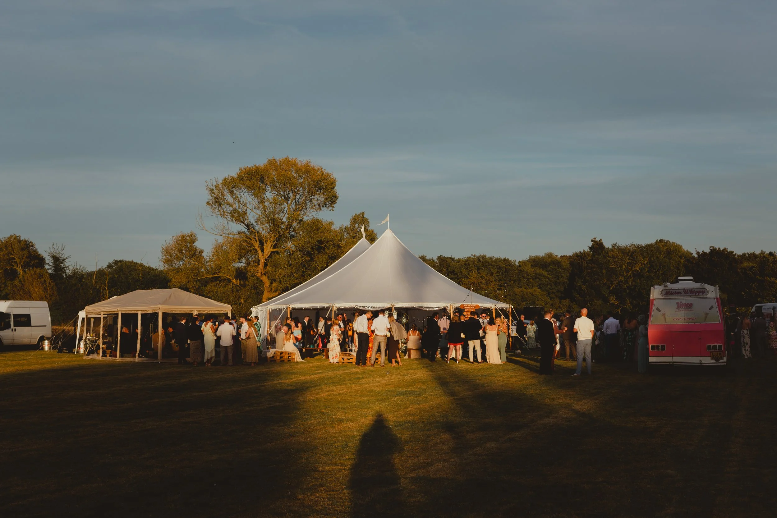 Sunset wide shot of a wedding reception at a festival outdoor with a marquee and ice cream van in Suffolk countryside Lowestoft 