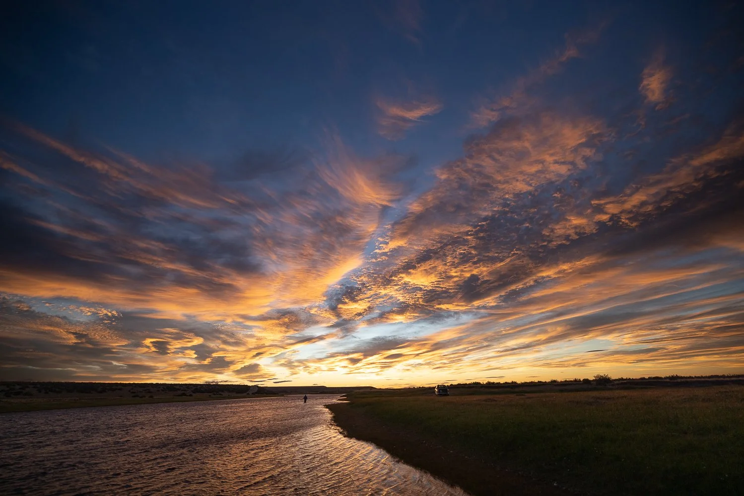 Solnedgang over en flod med farverige skyer på himlen.