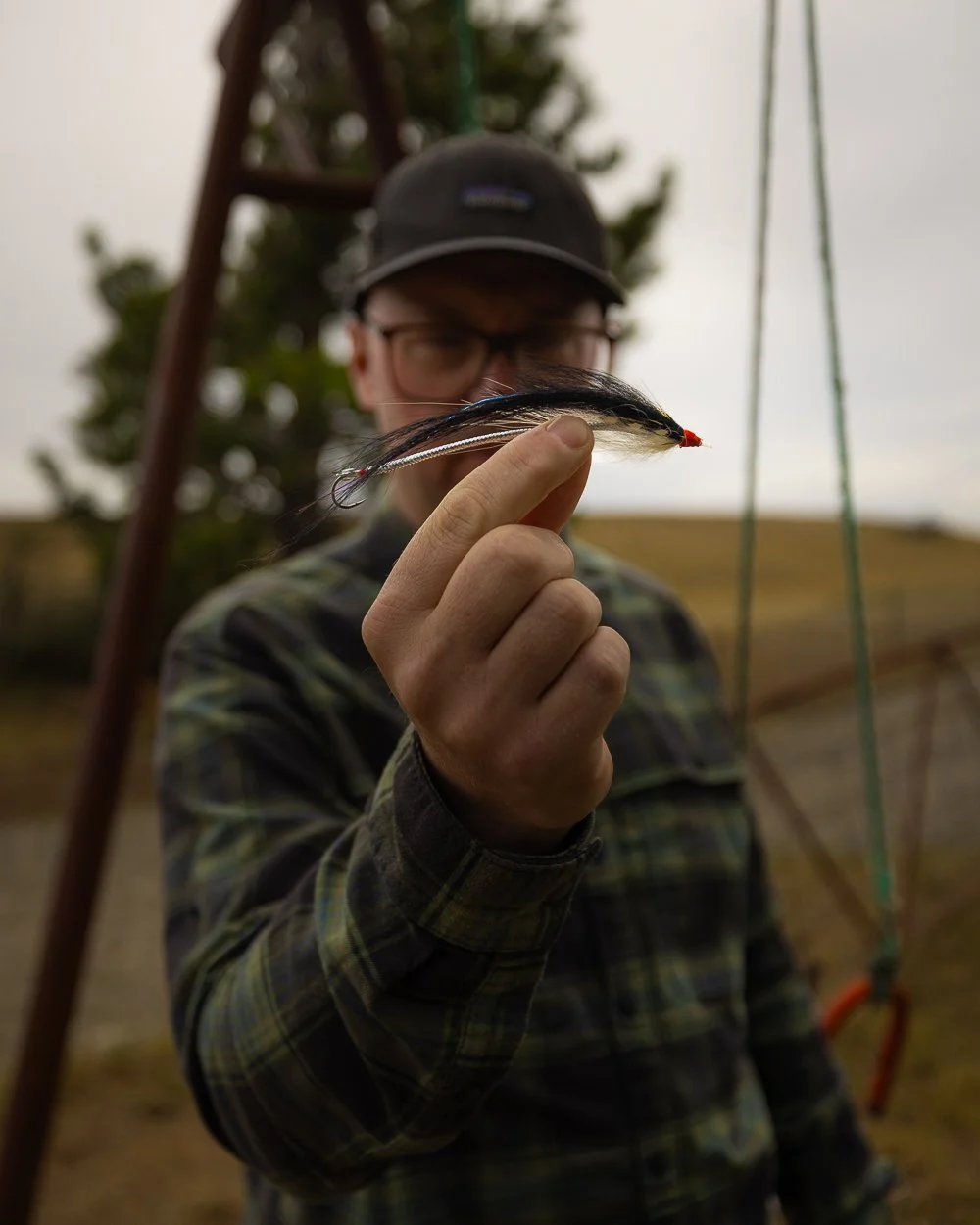 Person holder en fluefisk, med natur i baggrunden.