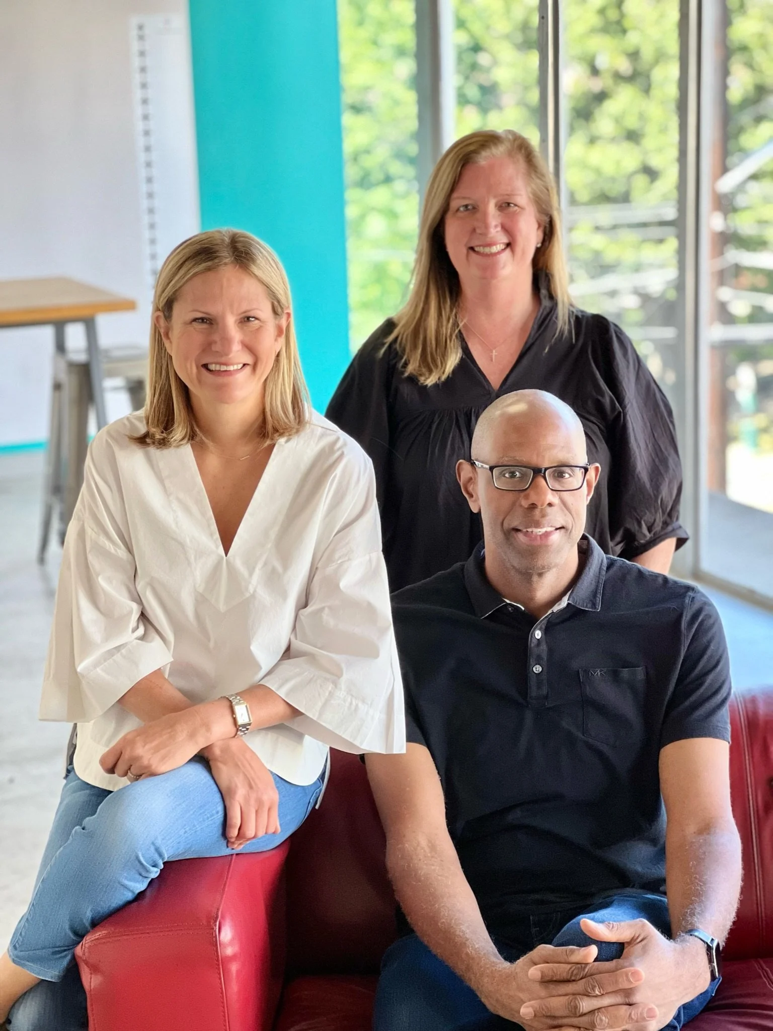 Three founders sit together. Two women and a man with a window and classroom features behind them.