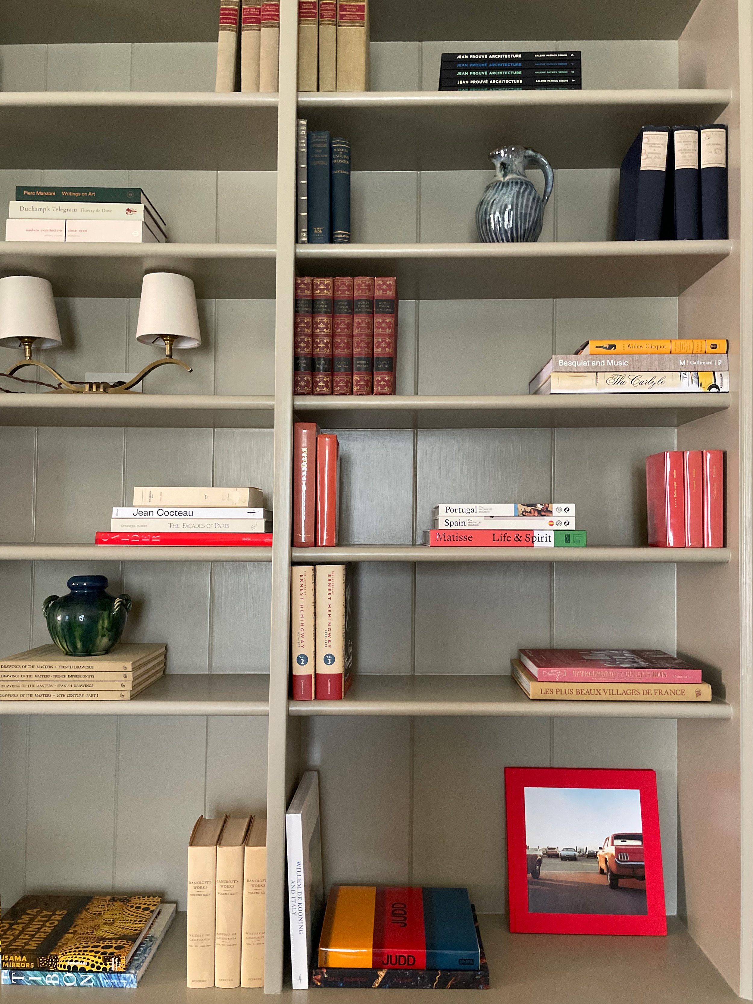 A bookshelf filled with various books, decorative ceramics, and photo frames.