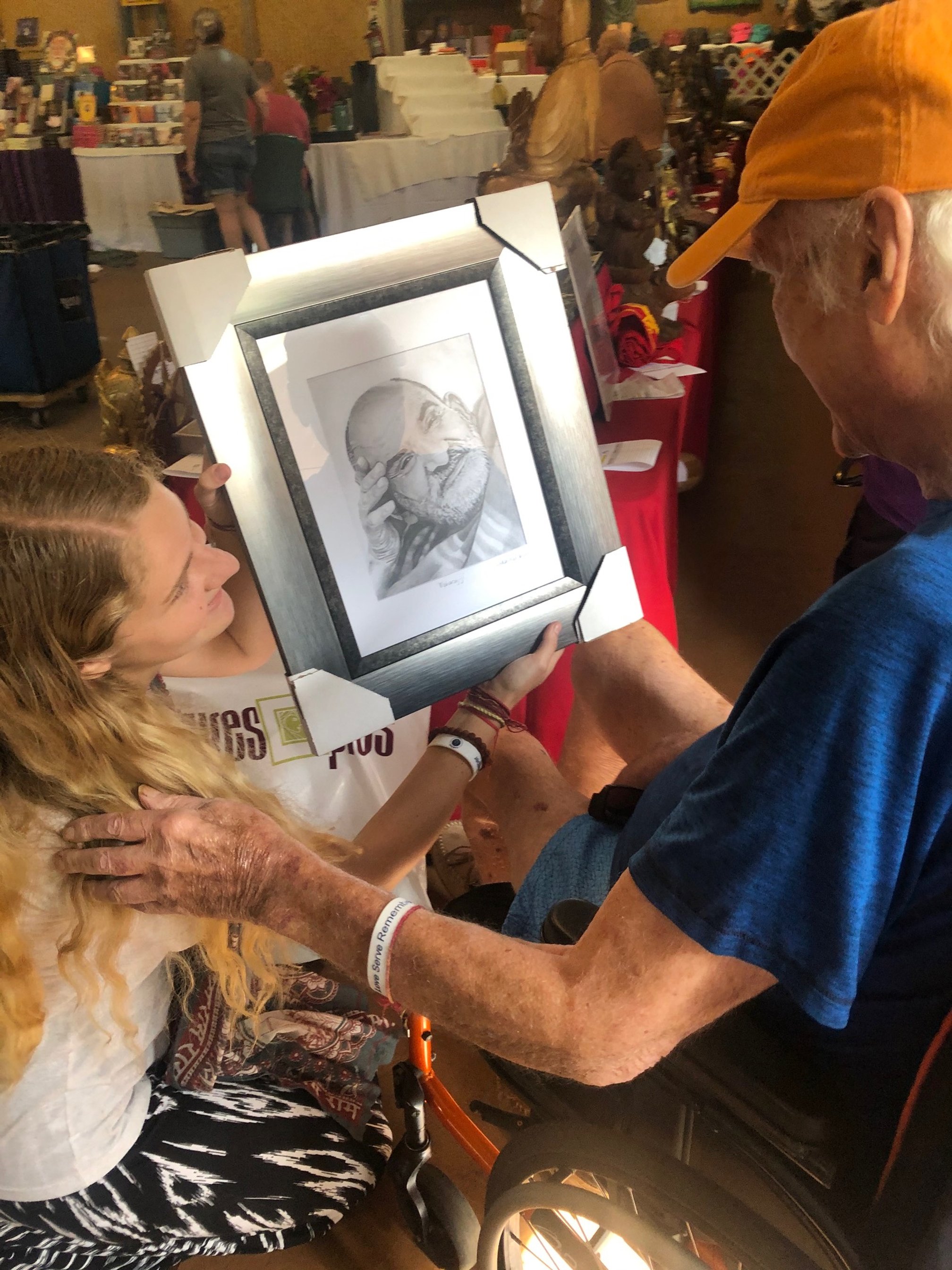 Photo of Lakshmi kneeling down to present her framed portrait drawing of Maharaj-ji to Ram Dass