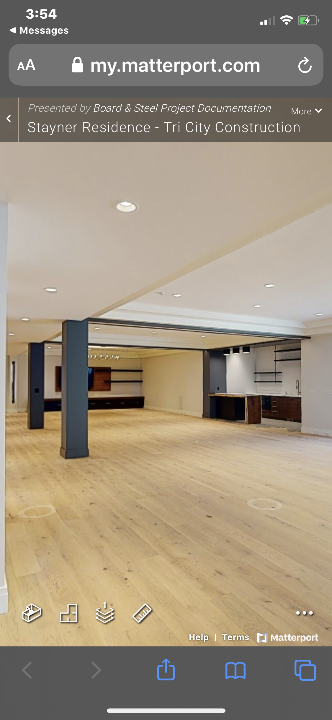 Interior view of an empty open-concept living space with wooden flooring, modern kitchen area, and ceiling-mounted spotlights.