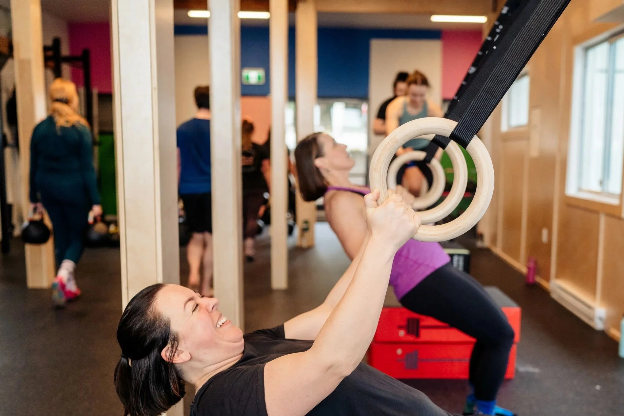Woman performing a kettlebell exercise in a gym, wearing a black sports bra and blue leggings.
