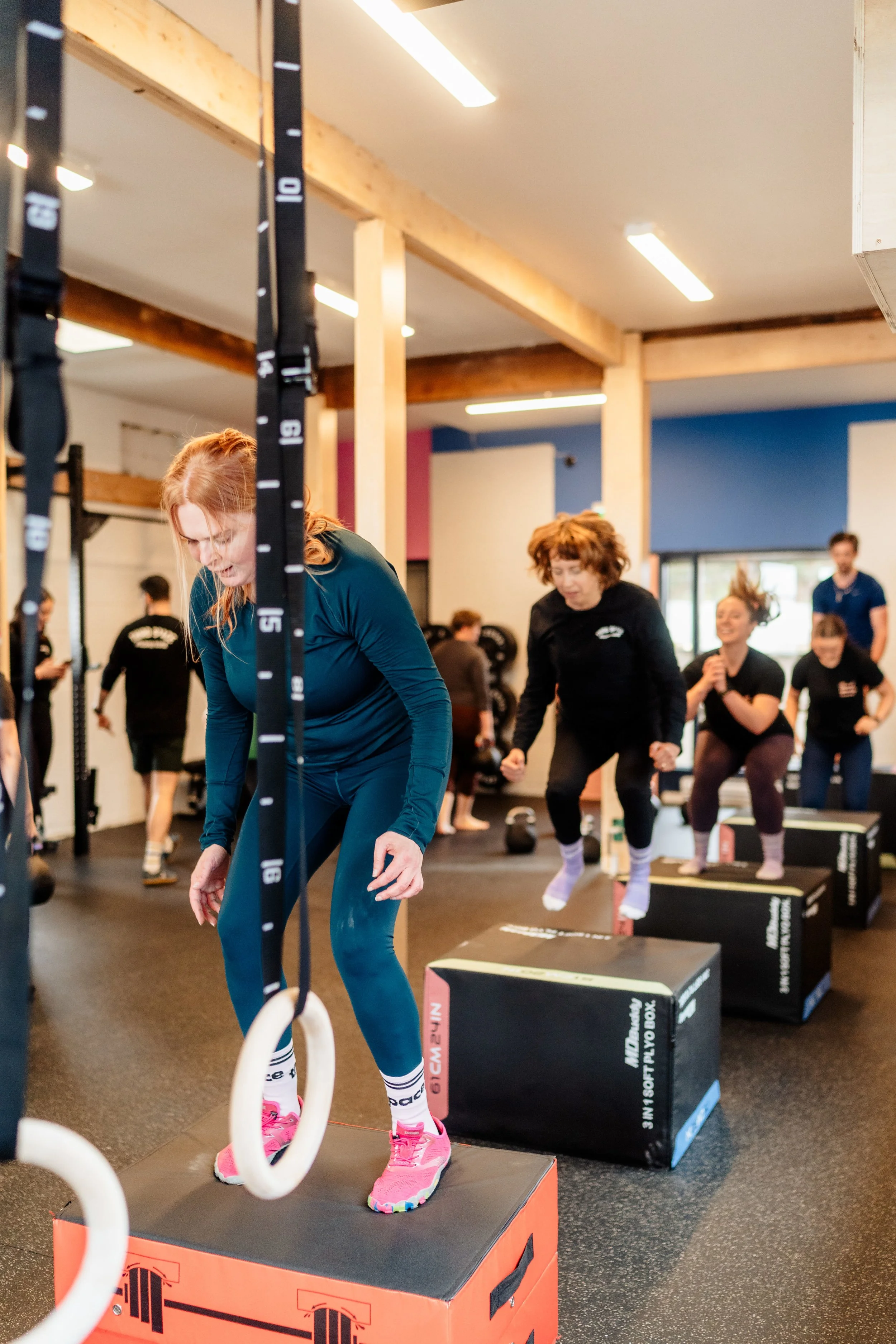 Group fitness class performing kettlebell squats in a gym.