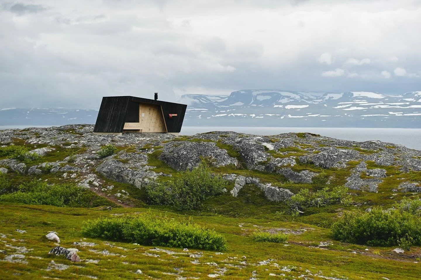 Arctic Norway: On the edge of the wide Tanafjord lies a small, open-for-all mini cabin. Koppmollbukta is surrounded by tundra slopes, tiny birch woods and expansive fjord views. Here, you can light a fire and take shelter. It is achitecture made simp