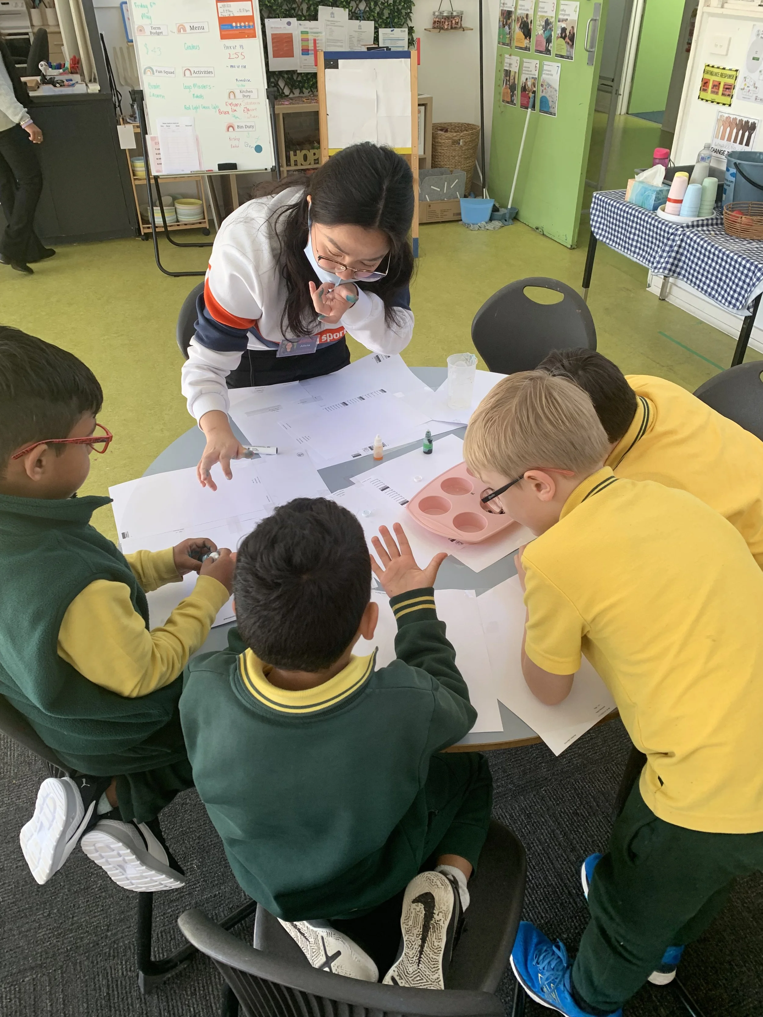 Teacher helping elementary school children with a classroom art project at a table