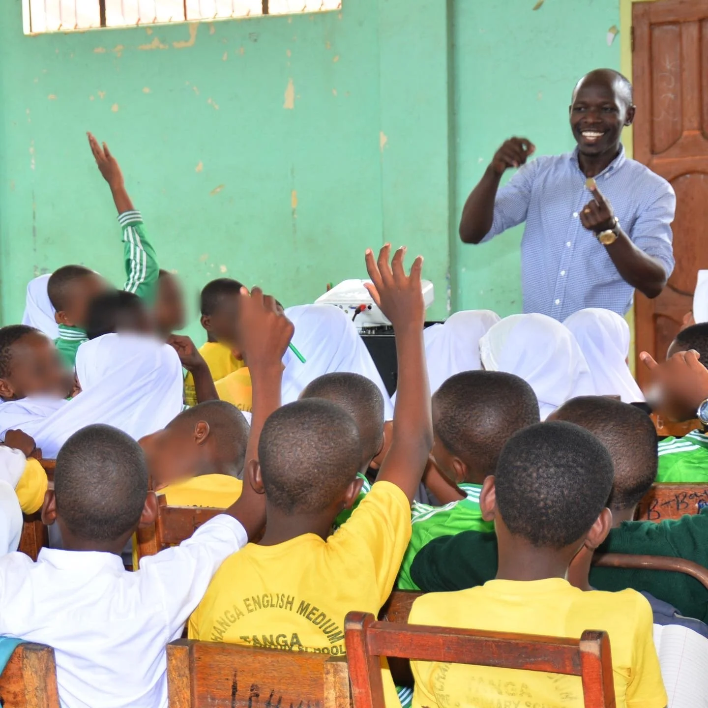 Teacher leading an interactive classroom lesson as elementary students raise their hands.