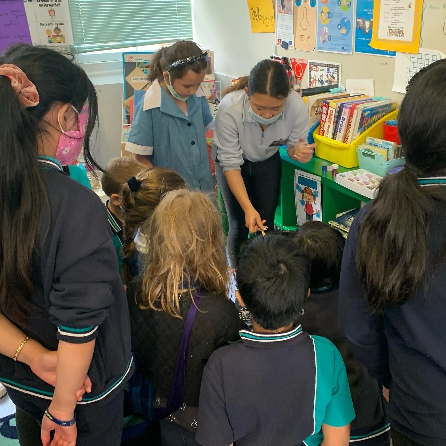 Teacher demonstrating an activity to a group of elementary school children in a colorful classroom