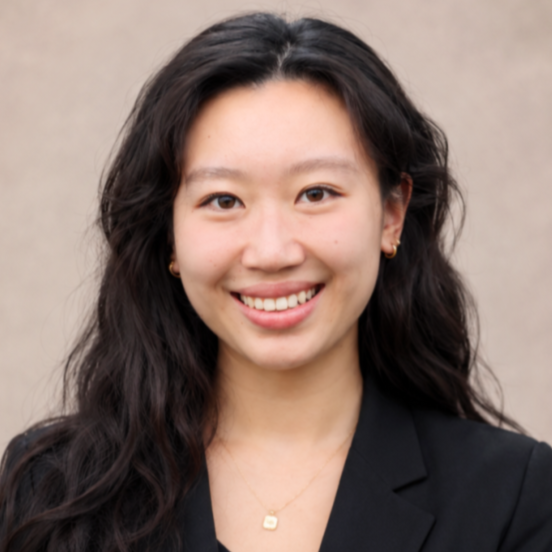 Professional headshot of a smiling woman with long dark hair wearing a black blazer and gold necklace
