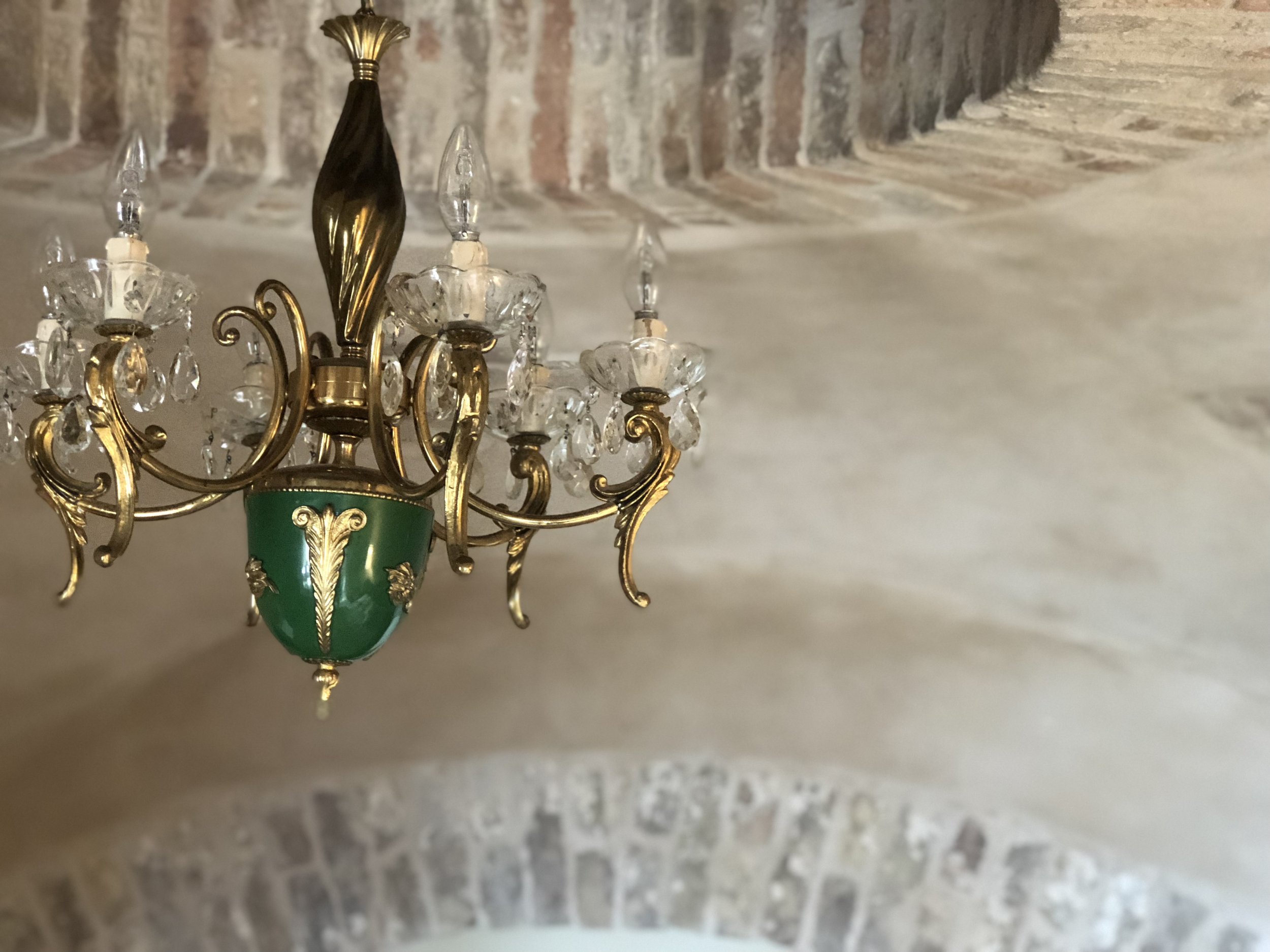 Ornate gold and green chandelier with crystal accents against a stone ceiling. Il Nido Apartment, Appassionata, Fractional Ownership, Le Marche, Italy.