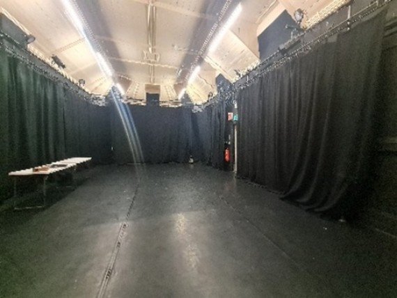 An empty black Box space with curtains and a white celling.