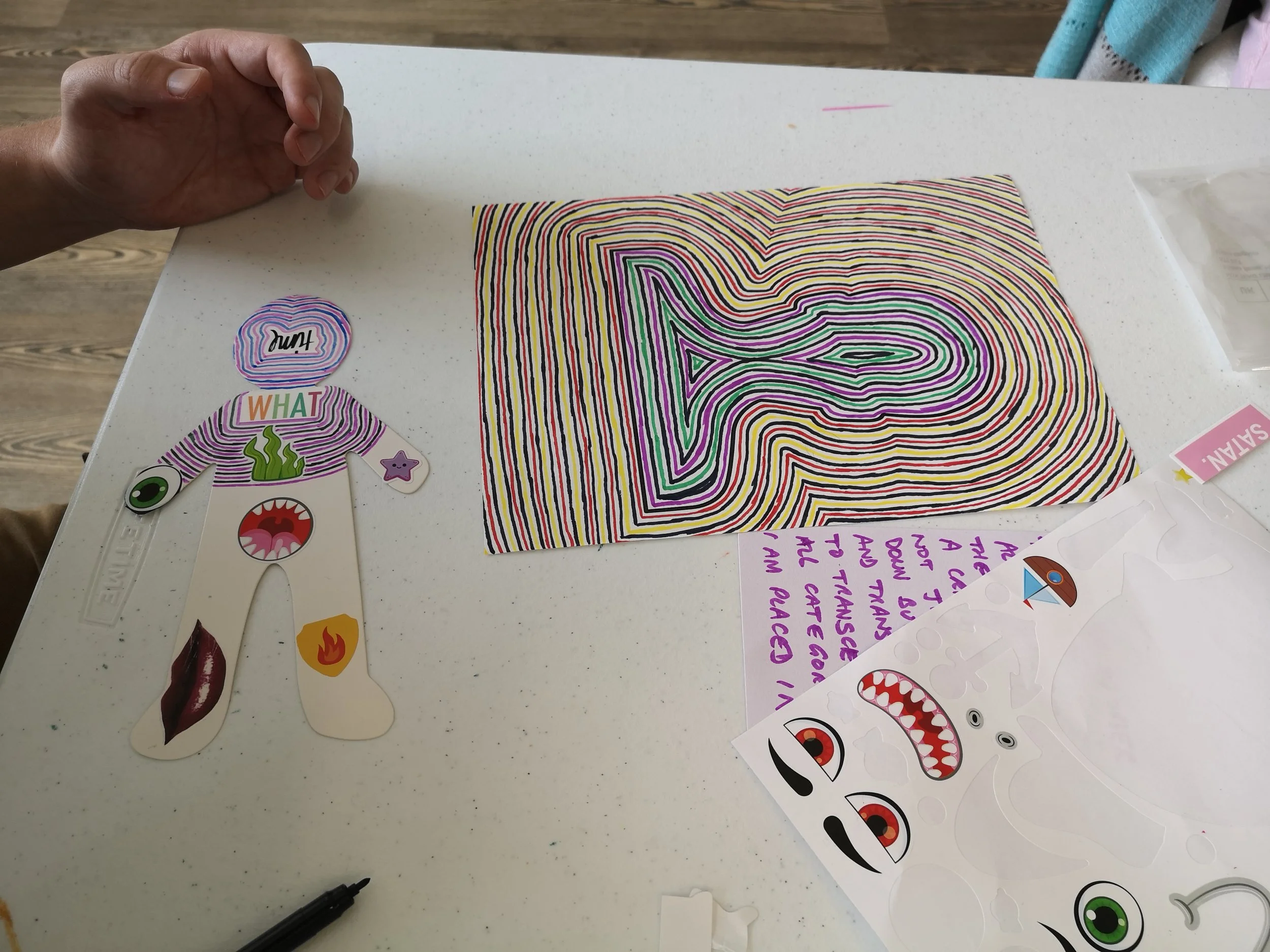a outline of a human head with centric rings around the outside. Left a half painted anon with purple colour and stickers .