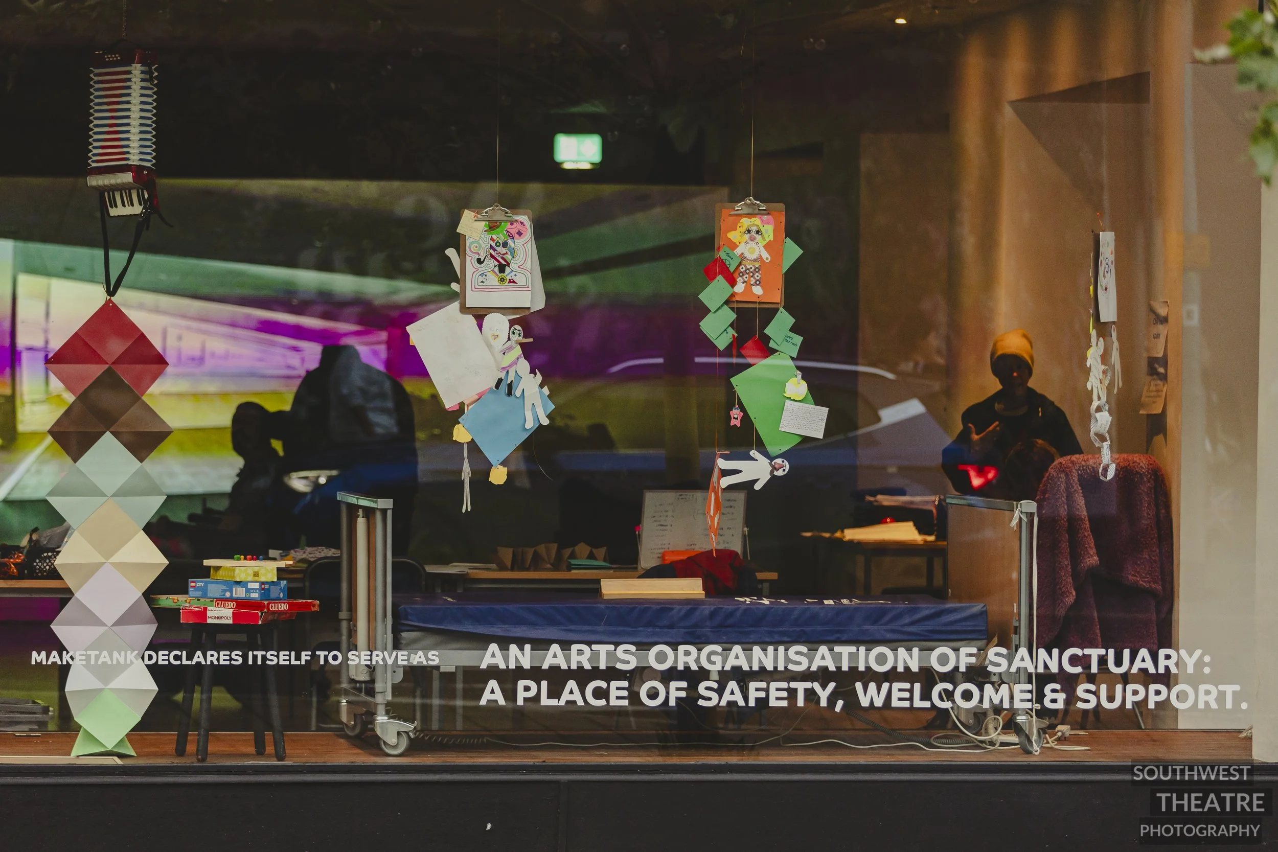 Shop front window shows a colurful set including a medical bed, ball games and the projection.
